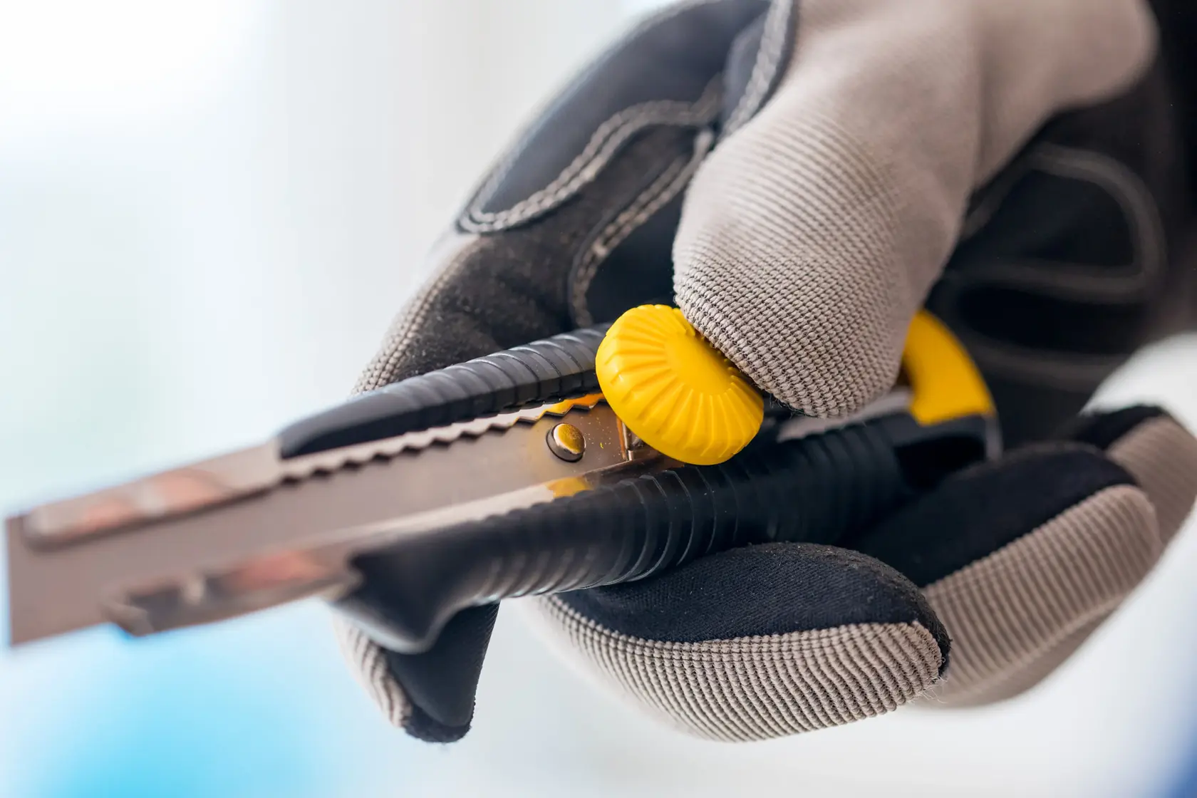 STANLEY 0-10-418 Cuttermesser mit gelbem Drehknopf, in behandschuhter Hand, Nahaufnahme.