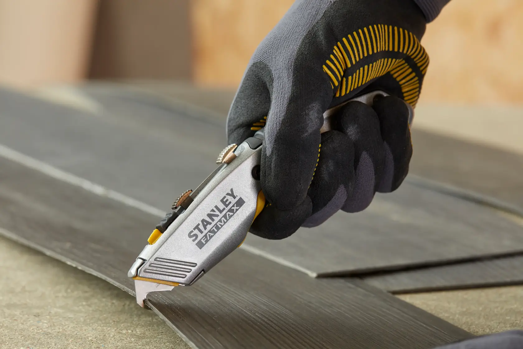 Stanley 0-10-789 Messer in Handschuh schneidet dunklen Laminatboden.