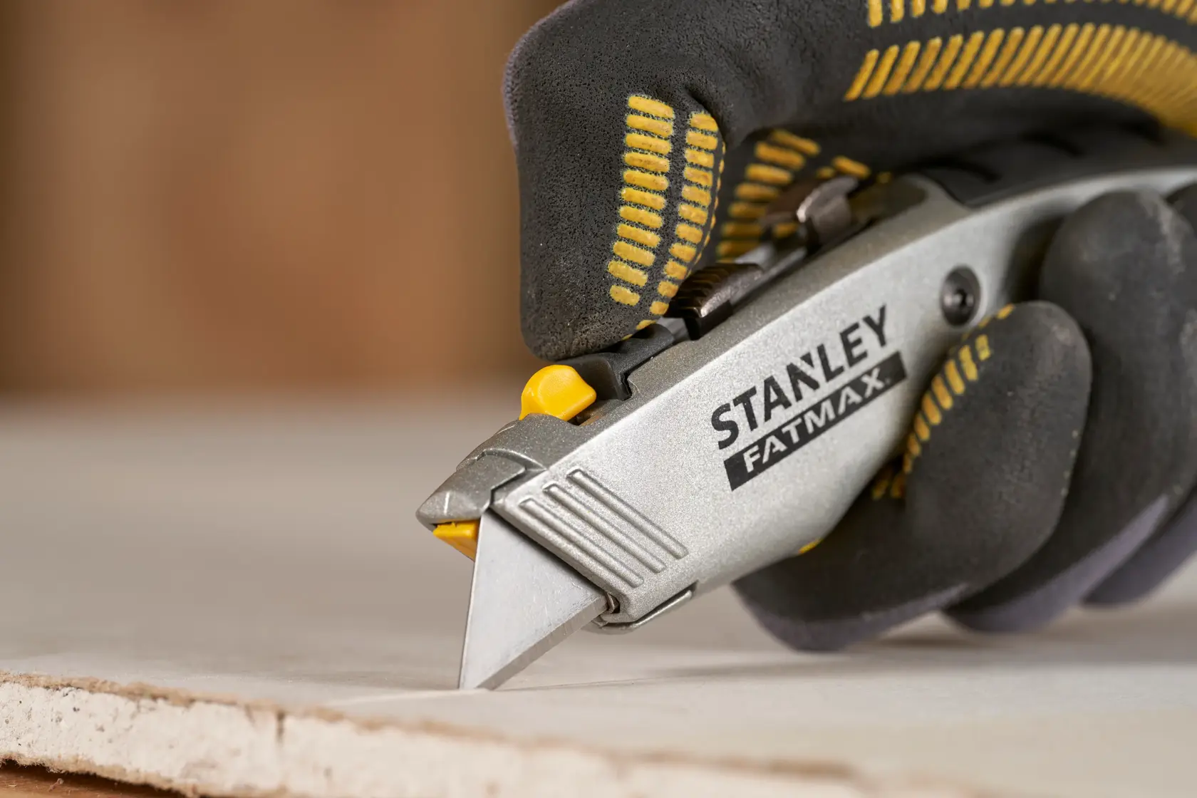 Stanley 0-10-789 Universalmesser im Einsatz beim Schneiden von Gipskarton, Nahaufnahme mit Handschuh.