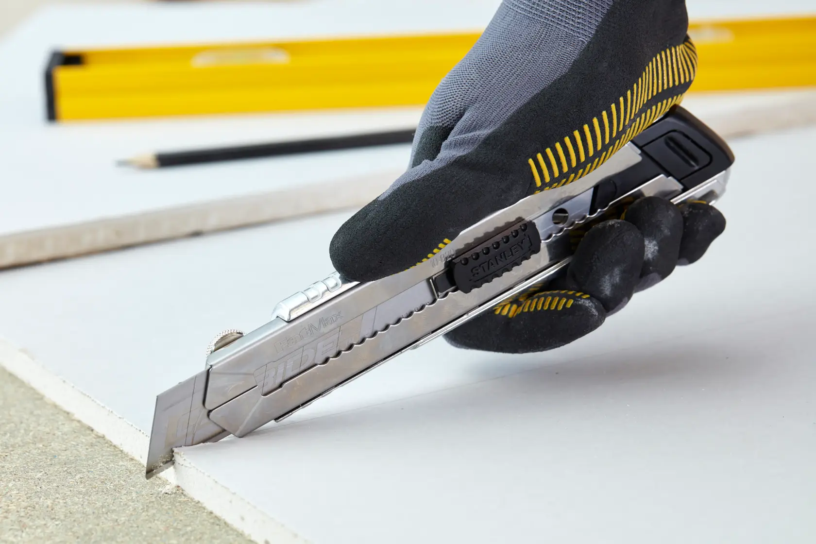 STANLEY 0-10-820 Universalmesser schneidet Trockenbau, gehalten von einer behandschuhte Hand, Seitenansicht Foto.