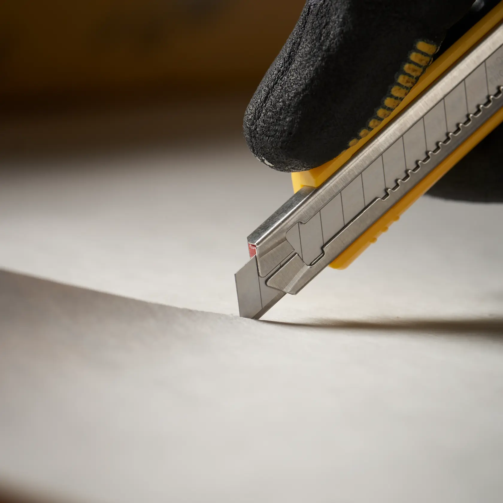 STANLEY 0-11-300 Messer schneidet Papier, gehalten von behandschuhter Hand, Nahaufnahme, Produktfoto.