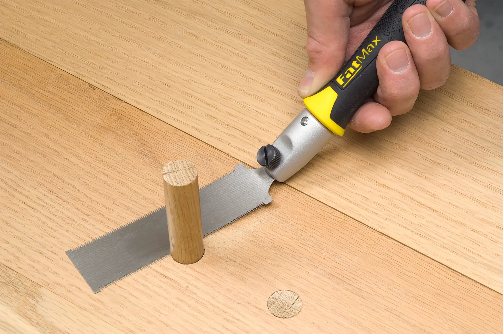 STANLEY 0-20-331 Flachsäge mit schwarz-gelbem Griff schneidet Holzdübel, Nahaufnahme.