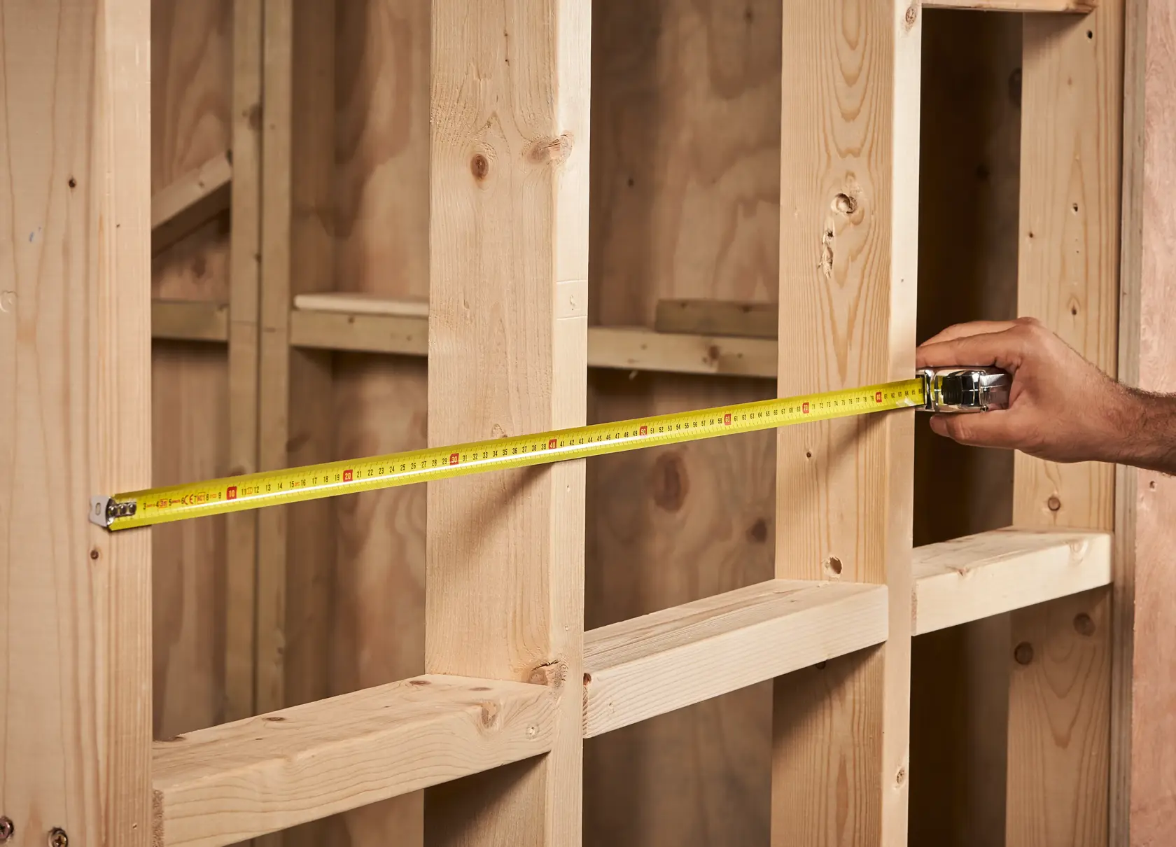 STANLEY 0-33-522 Maßband über Holzständerwand gespannt, Produkt in Anwendung, Nahaufnahme.