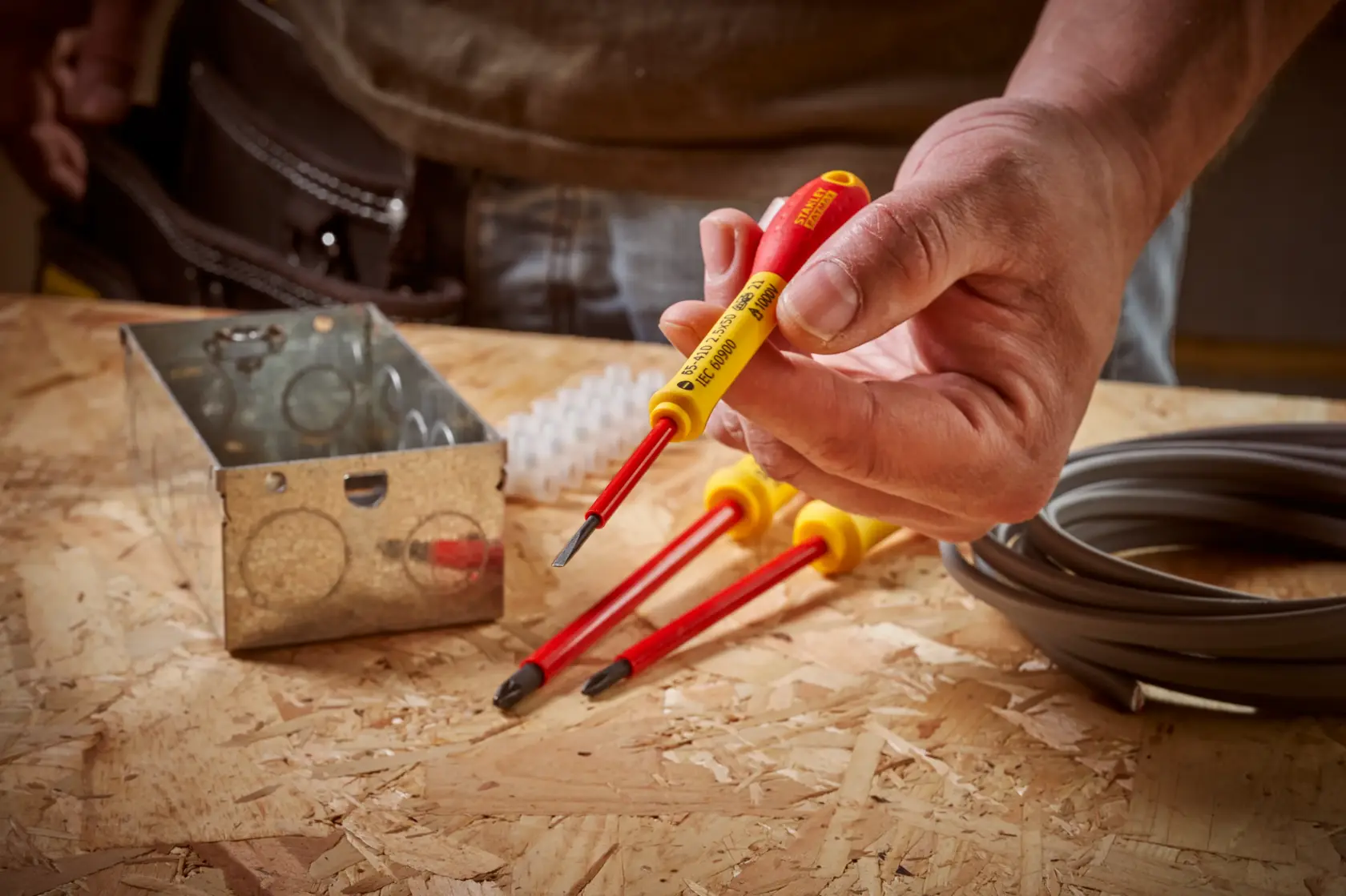 STANLEY 0-65-410 isolierter Schraubendrehersatz mit roten und gelben Griffen auf Werkbank mit Elektromaterial.