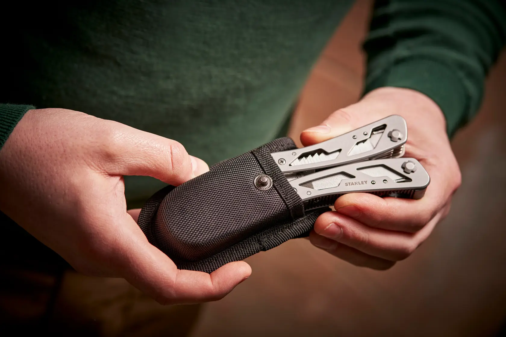STANLEY 0-84-519 Multitool im schwarzen Etui in Händen gehalten, Nahaufnahme.