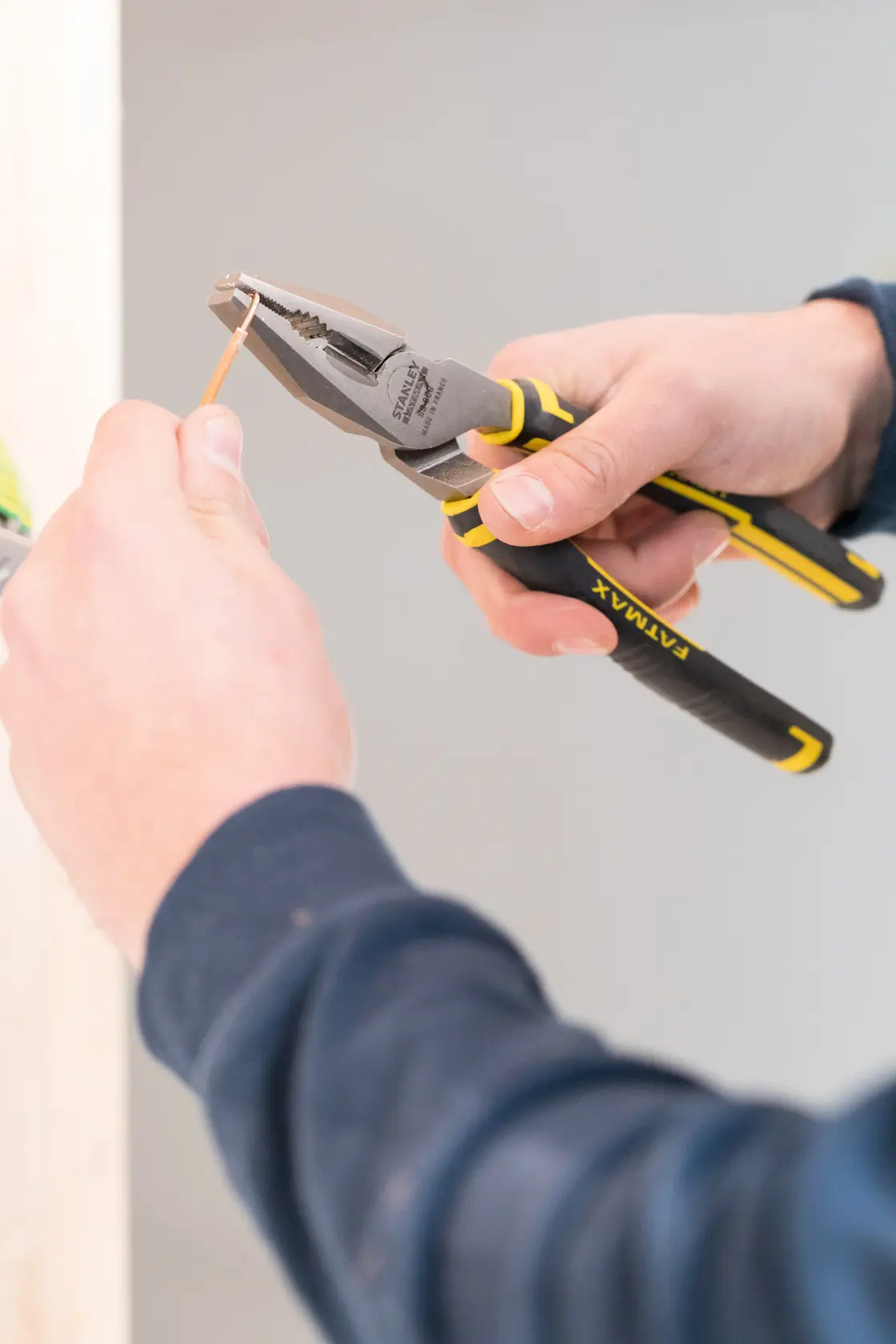 STANLEY 0-89-868 Zange schneidet Draht, Nahaufnahme des schwarz-gelben Werkzeugs in der Hand.