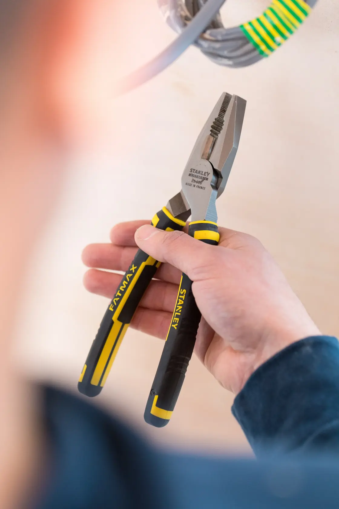 STANLEY 0-89-868 Zange mit schwarz-gelbem Griff, in der Hand gehalten, beim Arbeiten an Elektrokabeln.