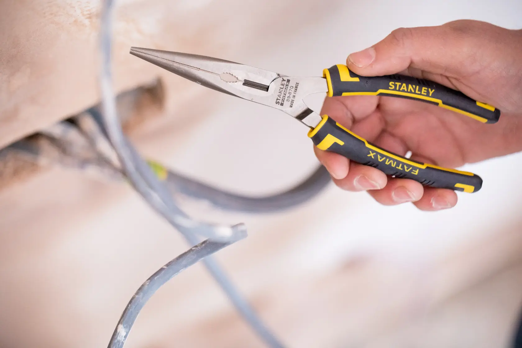 Stanley 0-89-870 FATMAX lange Nasezange mit schwarzen und gelben Griffen greift Elektrokabel.