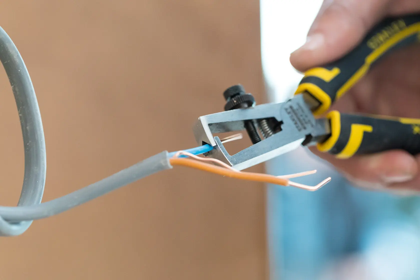 STANLEY 0-89-873 Abisolierzange schneidet Isolierung von Elektrokabel, Nahaufnahme.