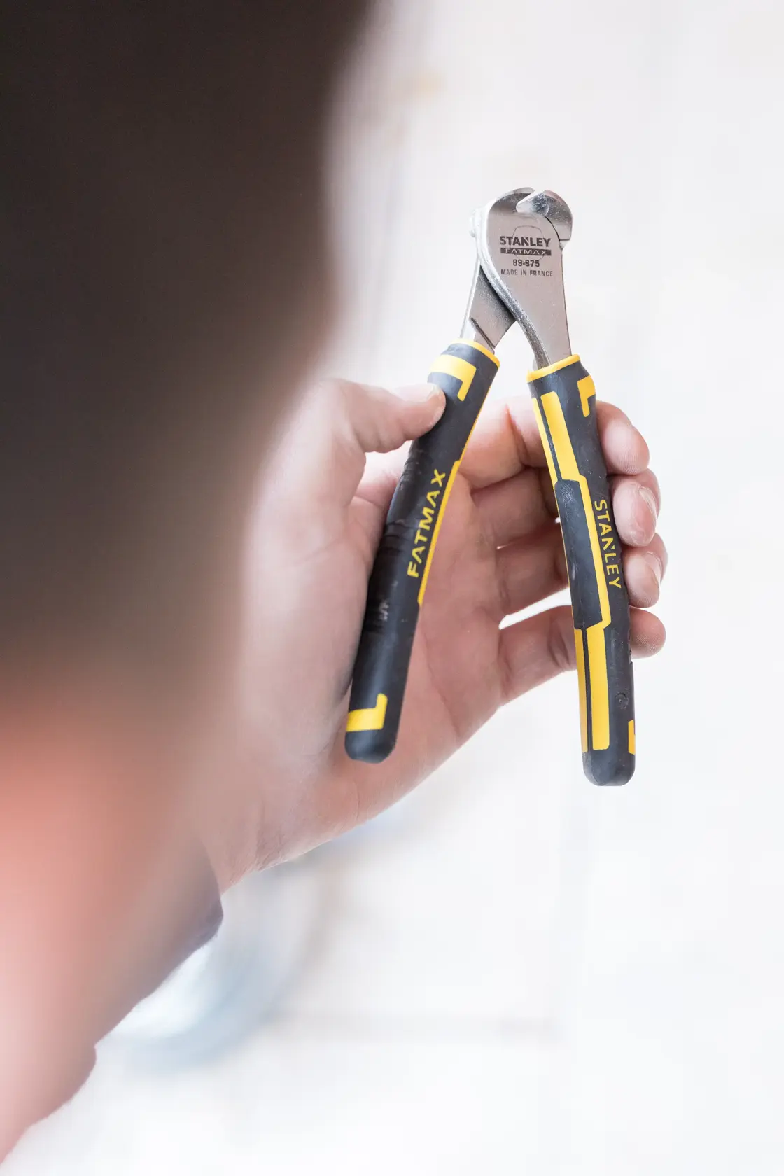Foto der STANLEY 0-89-875 FATMAX Endschneiderzange mit schwarzen und gelben Griffen in einer Hand gehalten.
