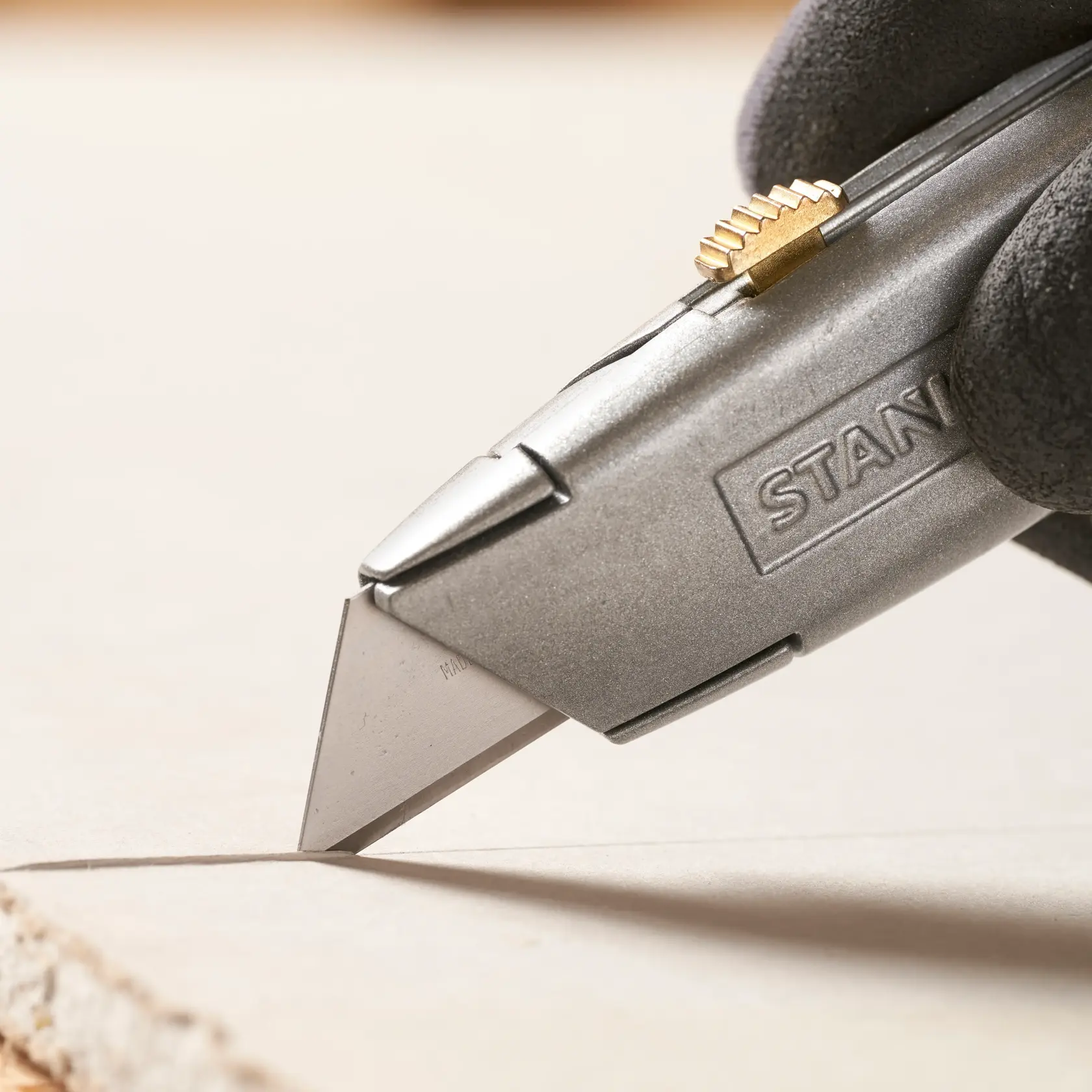 STANLEY 1-11-921 Universalmesser Nahaufnahme schneidet Material, silberner Körper mit Messing-Schieber.