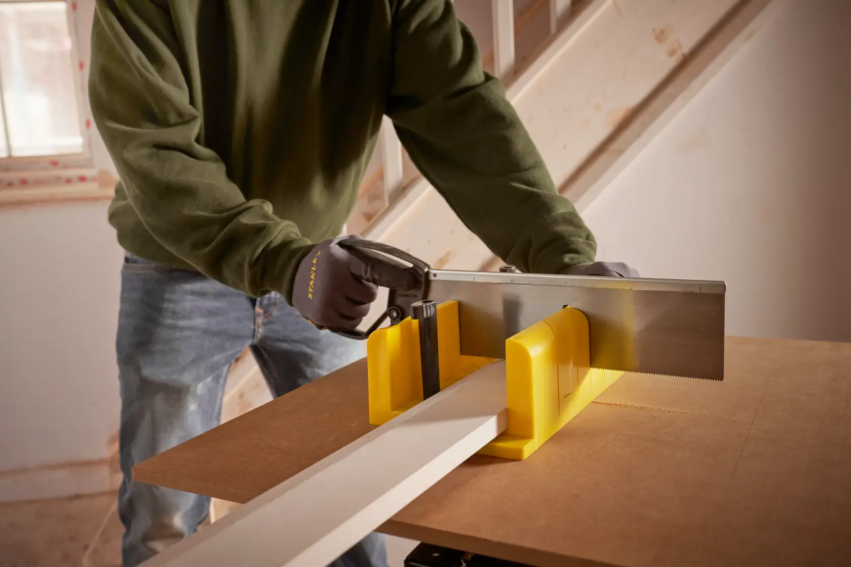 STANLEY 1-20-600 Handsäge und gelbe Gehrungslade zum Schneiden von Holz auf Werkbank, Nahaufnahme.