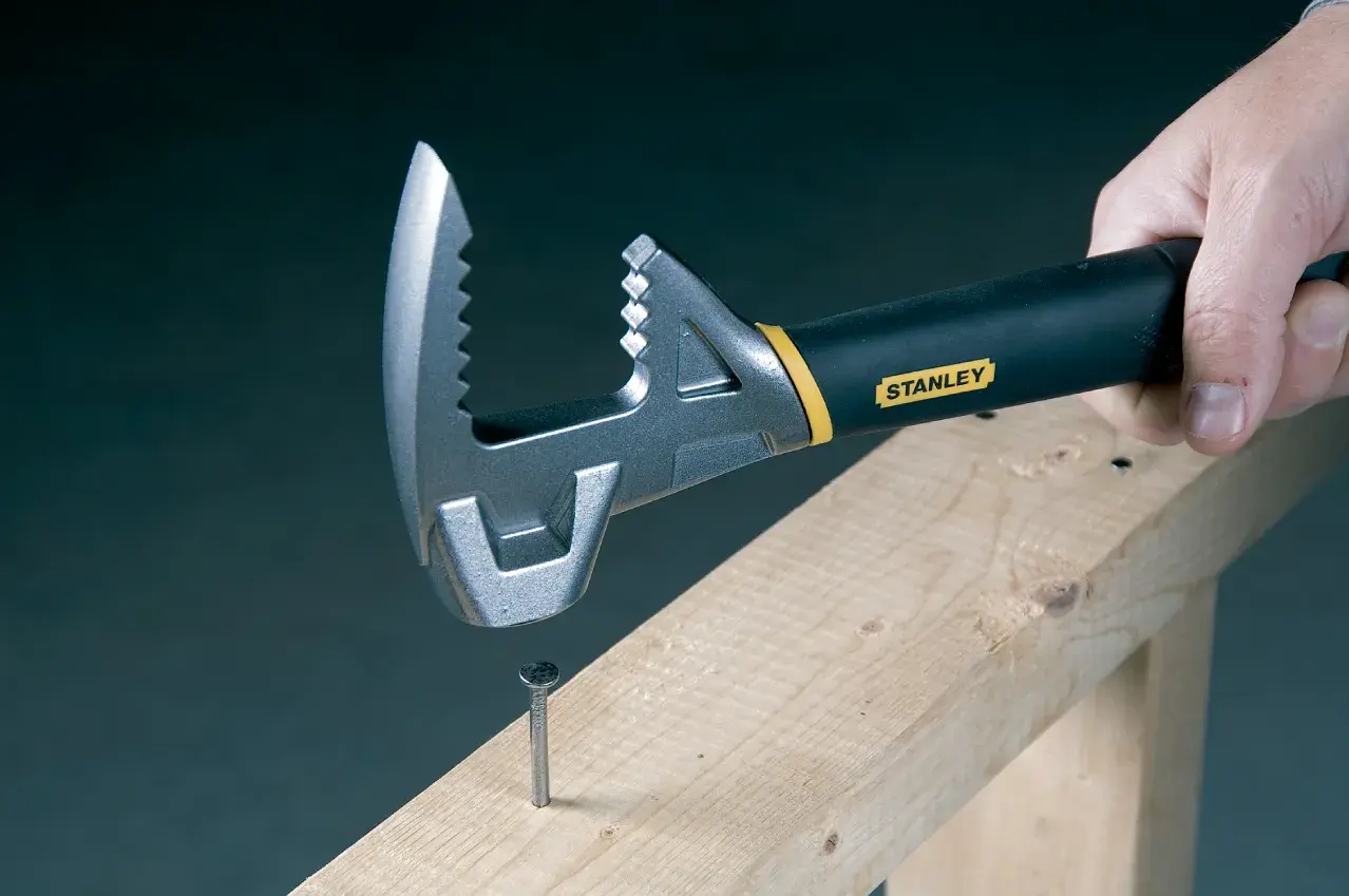 STANLEY 1-55-099 verstellbarer Schraubenschlüssel mit schwarzem Griff, hält einen Nagel auf Holzbalken, Nahaufnahme.
