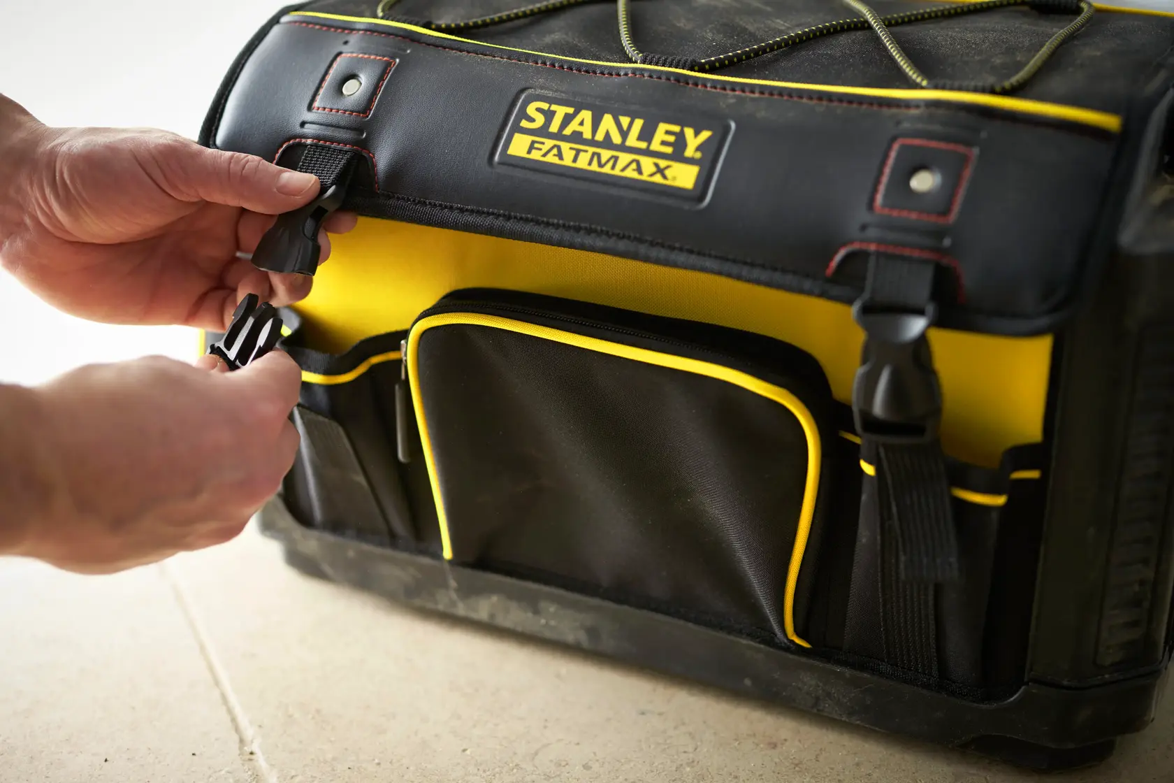 STANLEY 1-79-213 Werkzeugtasche, schwarz-gelb, Vorderansicht, Hände schließen Seitenverschluss.