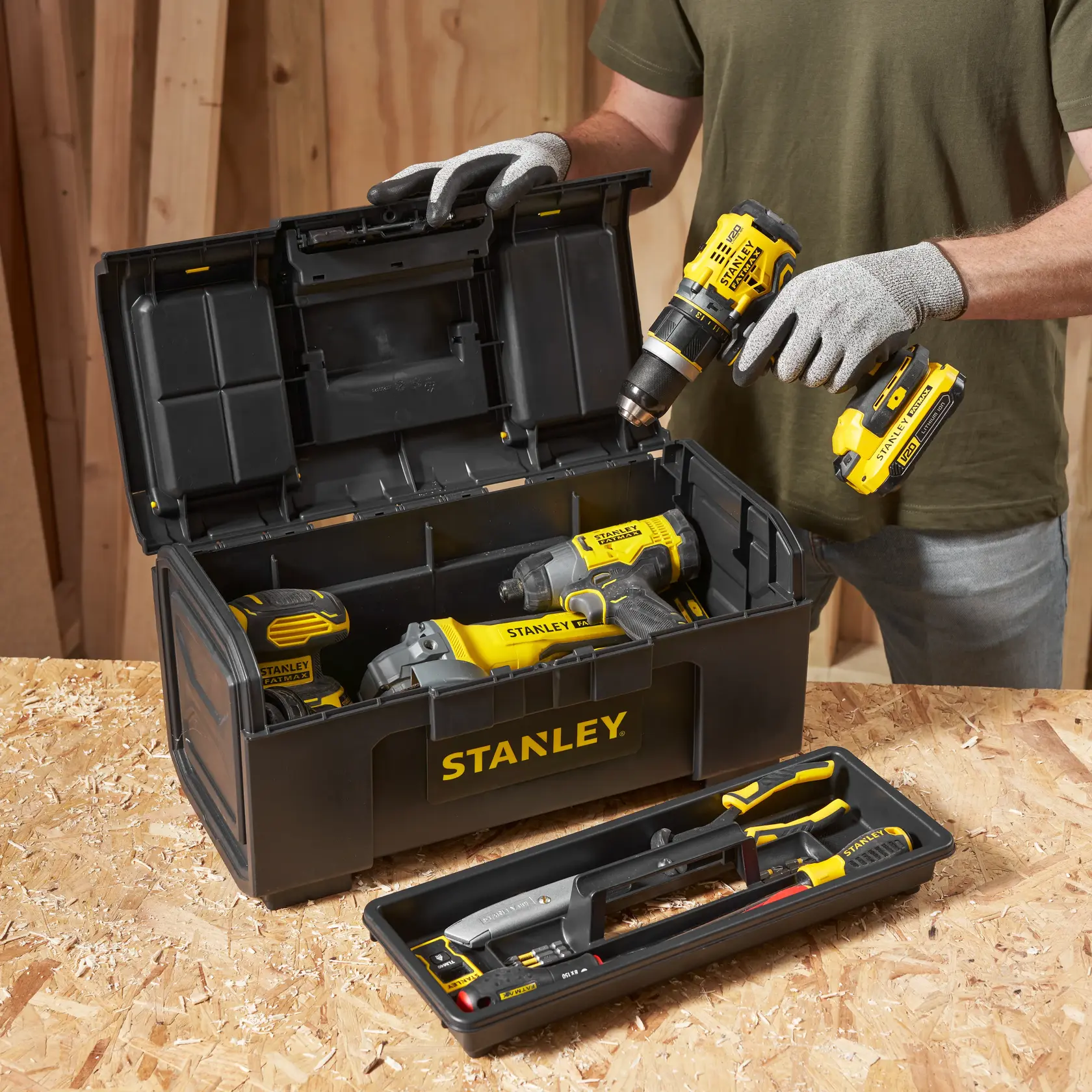 STANLEY 1-79-217 Werkzeugkasten mit gelben Elektrowerkzeugen und Handwerkzeugen auf Sperrholz, Vorderansicht.