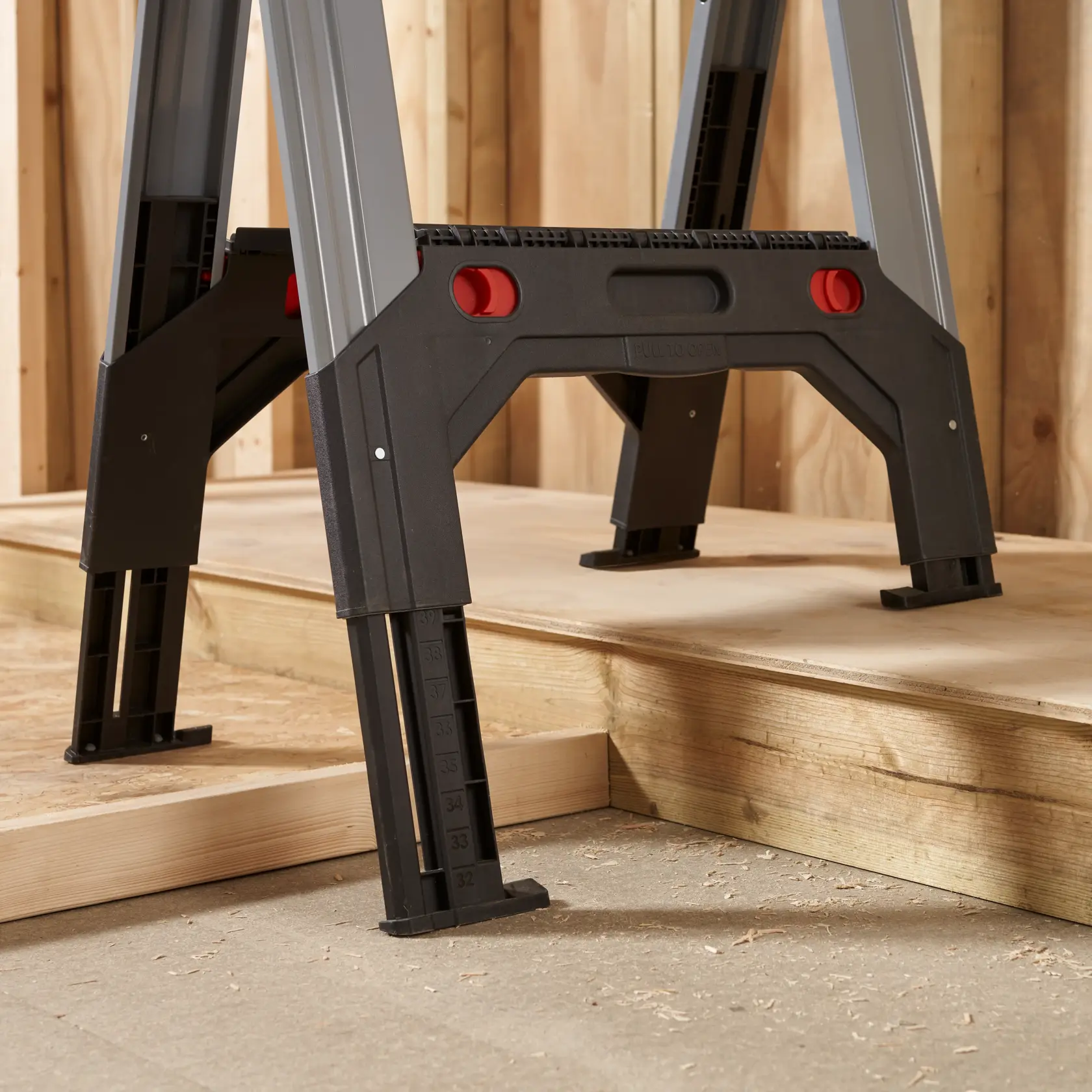 STANLEY 1-92-980 verstellbare Arbeitsplattformbeine mit Messmarkierungen, Nahaufnahme seitlich, auf Holzboden.