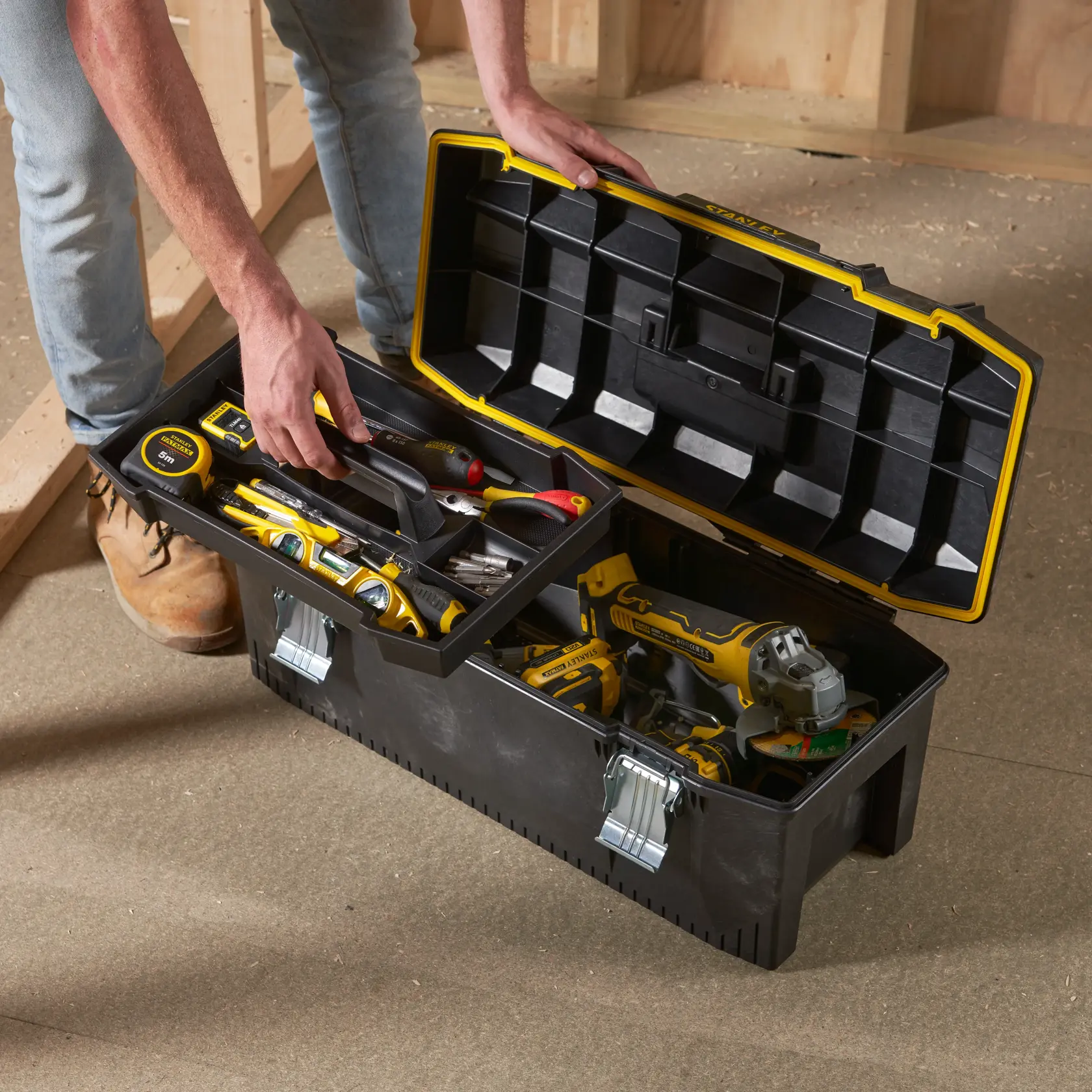 STANLEY 1-93-935 Werkzeugkasten mit gelbem Rand und Metallverschlüssen, offen, gefüllt mit Handwerkzeugen und Bohrmaschine.