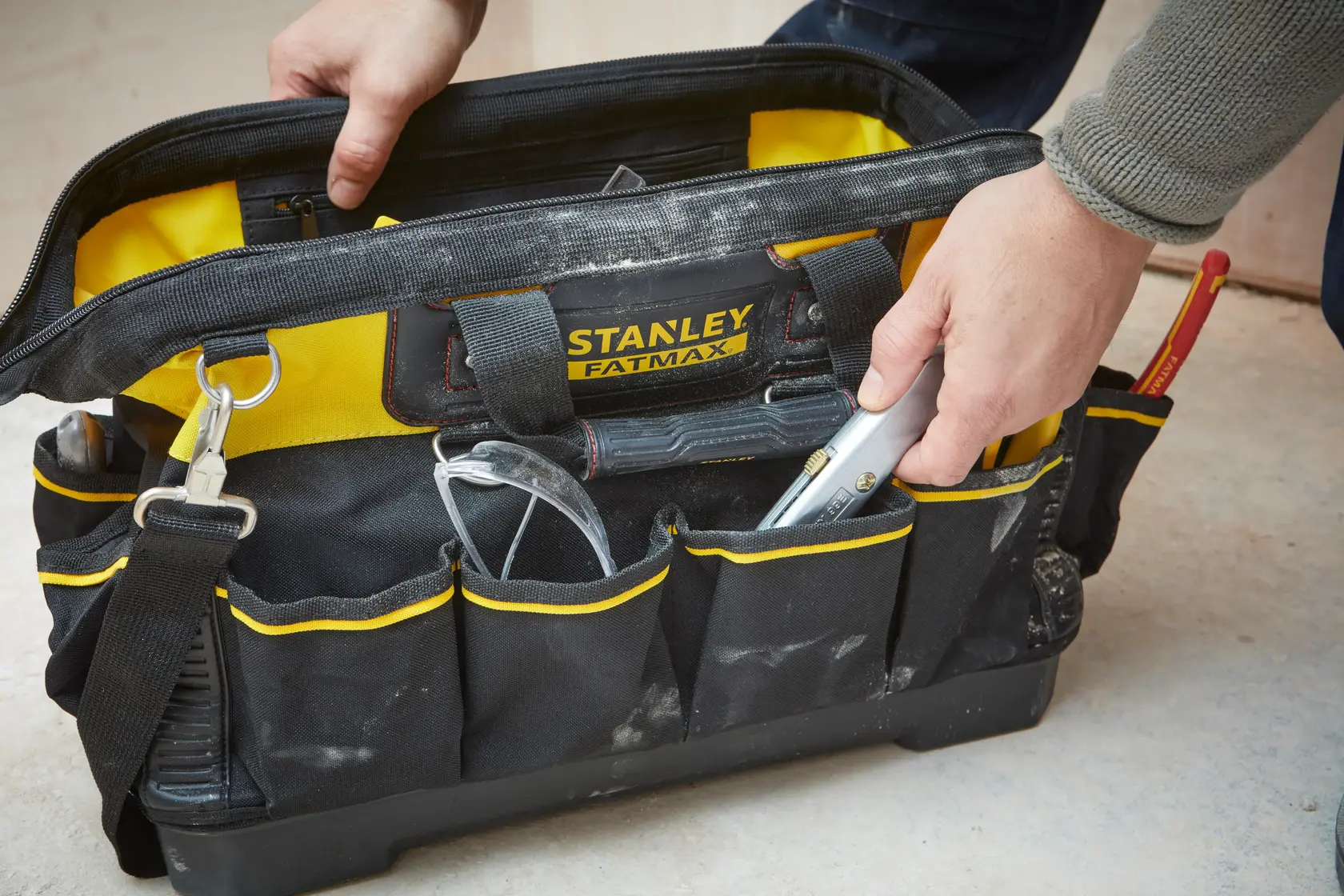 STANLEY 1-93-950 Werkzeugtasche mit gelben Akzenten, offen, gefüllt mit Handwerkzeugen, in Benutzung.