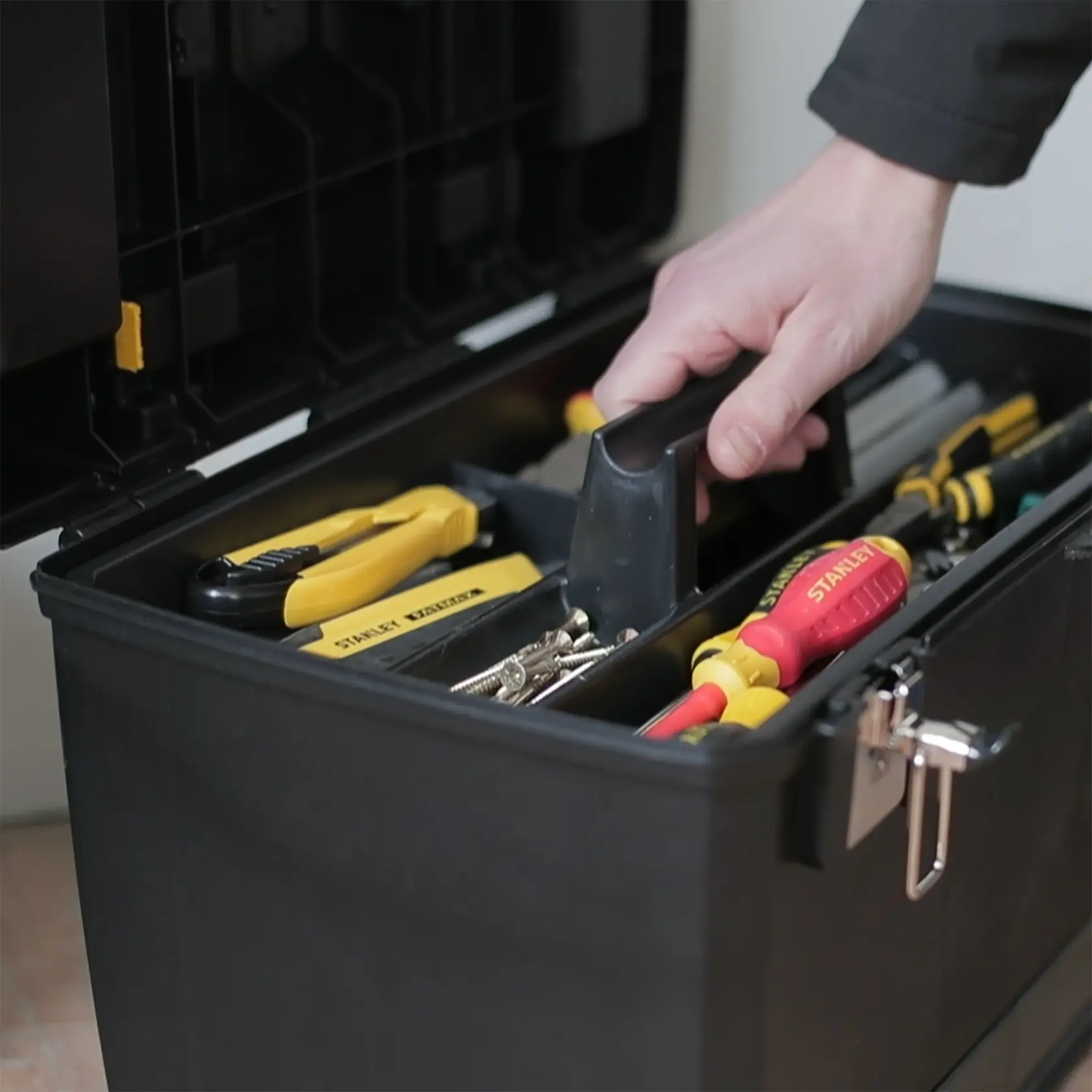 STANLEY 1-93-968 Werkzeugkasten mit Werkzeugen, Nahaufnahme mit Hand am Griff.