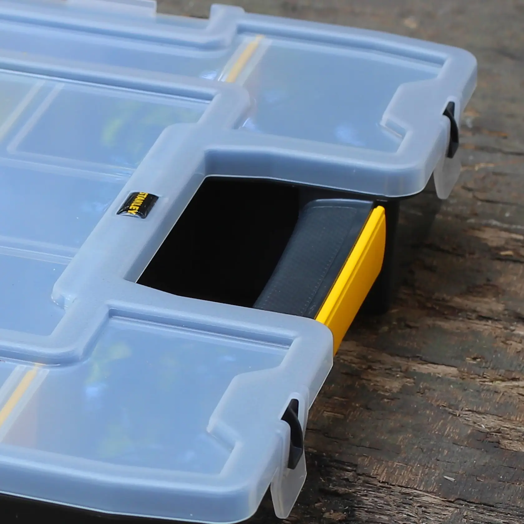 STANLEY 1-97-483 Kunststoff-Organizer mit durchsichtigem Deckel und gelbem Griff auf Holzoberfläche.