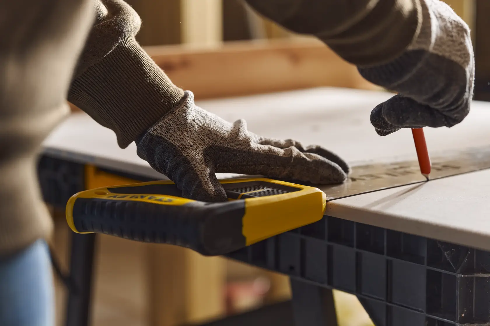 Foto der STANLEY 2-15-244 Handsäge auf Werkbank, Person mit Handschuhen markiert Holz.