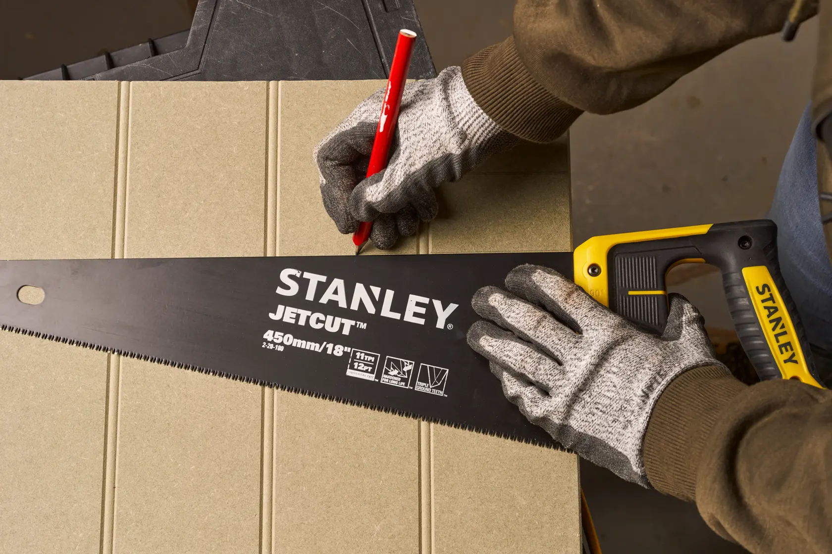Fotografie der STANLEY 2-20-180 Handsäge mit gelb-schwarzem Griff, zum Anzeichnen auf Platte verwendet.