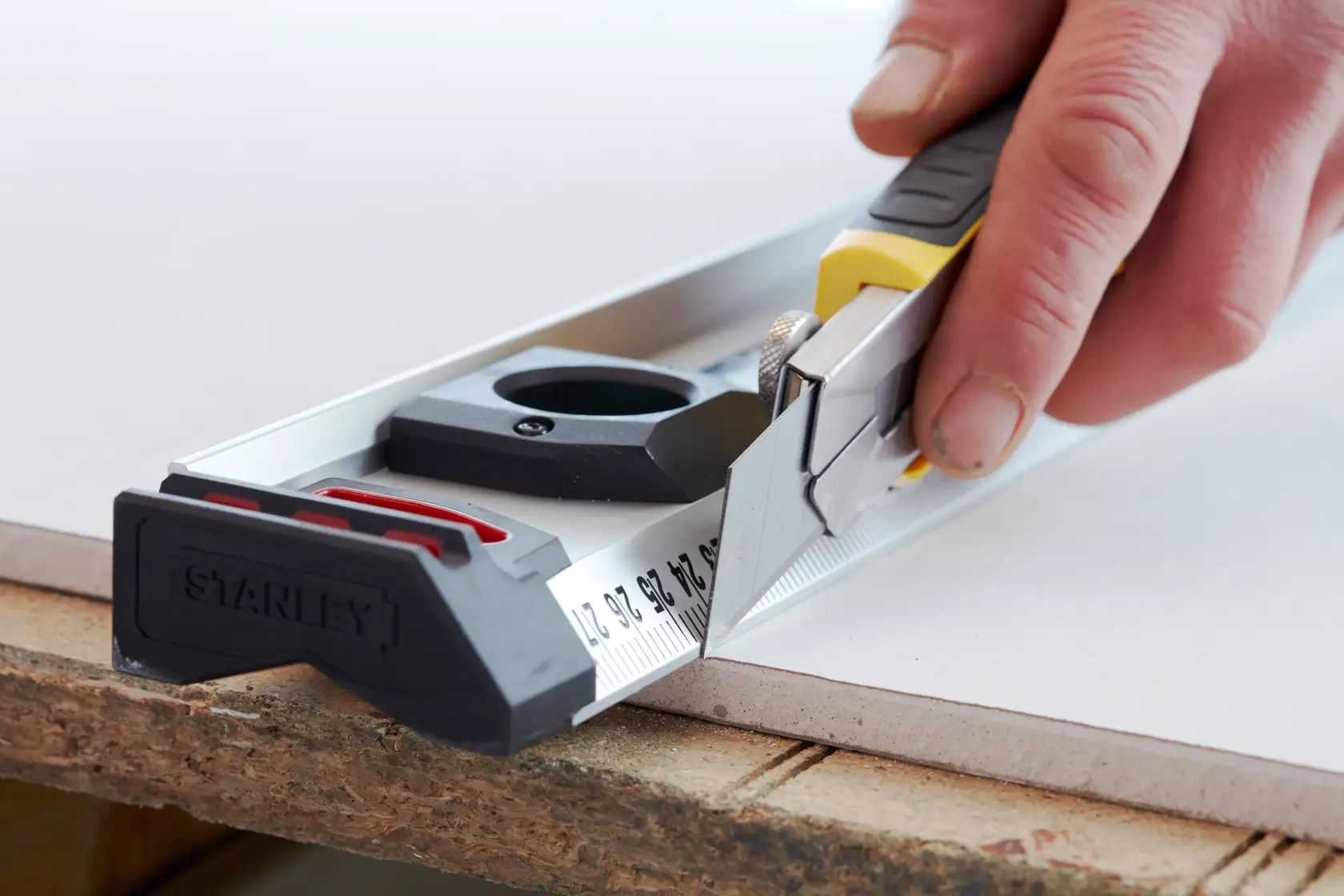 STANLEY 3-11-725 Universalmesser mit Linealführung beim Schneiden von Plattenmaterial, Nahaufnahme.