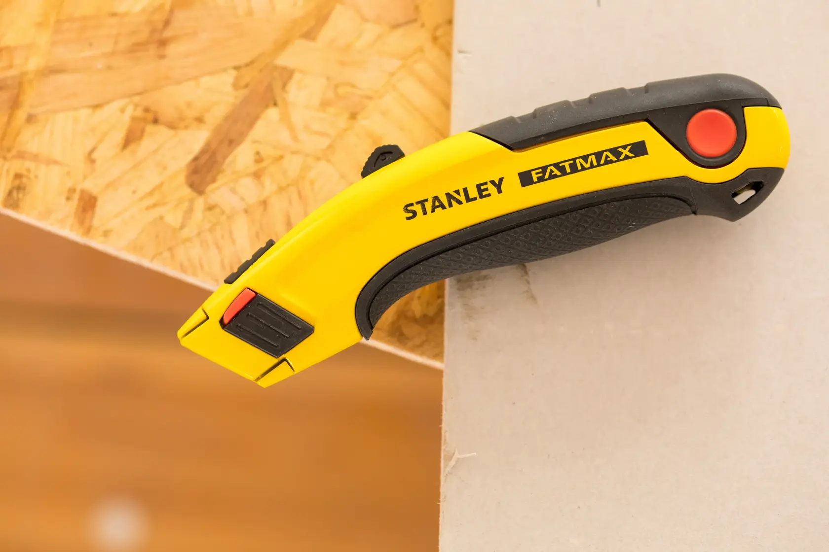 STANLEY 7-10-778 FATMAX Universalmesser, gelb und schwarz, Seitenansicht auf Holz und Gipskarton.