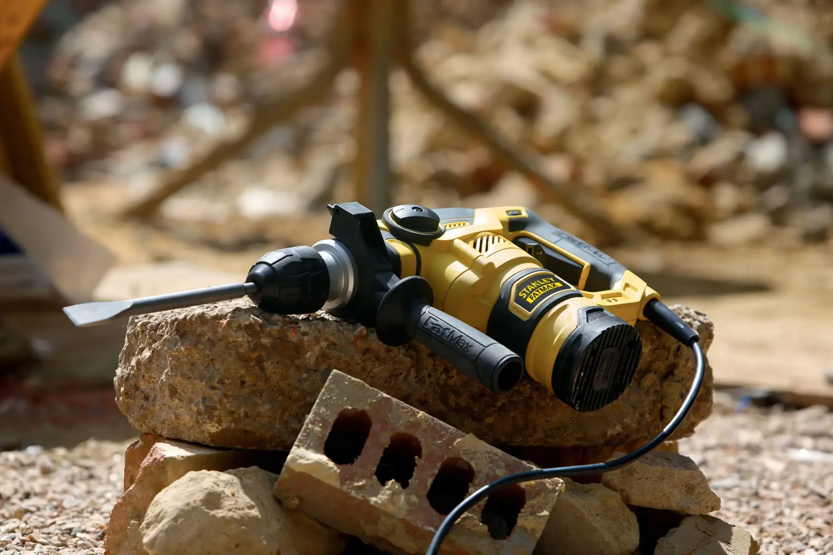 STANLEY FME1250K Bohrhammer mit Meißelaufsatz auf Bauschutt, dargestellt im Außenbereich.