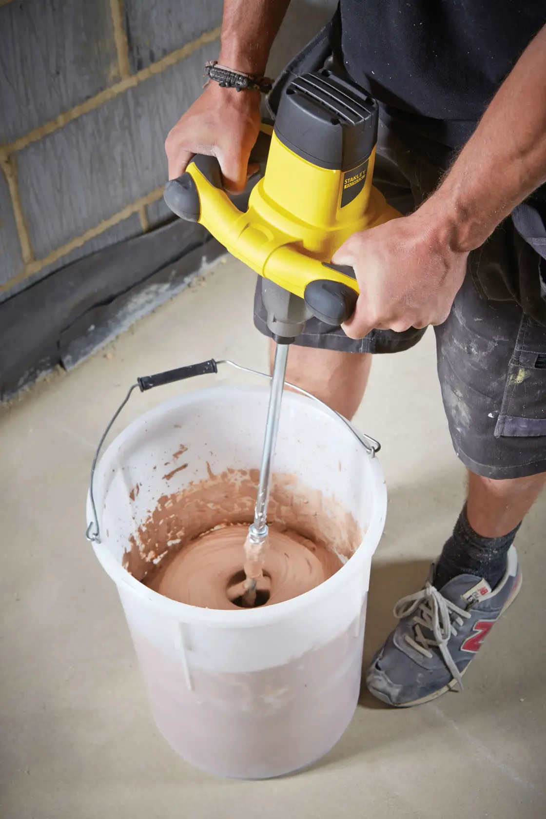 STANLEY FME190-QS Mischer zum Vermischen von Material in einem großen weißen Eimer auf einer Baustelle.