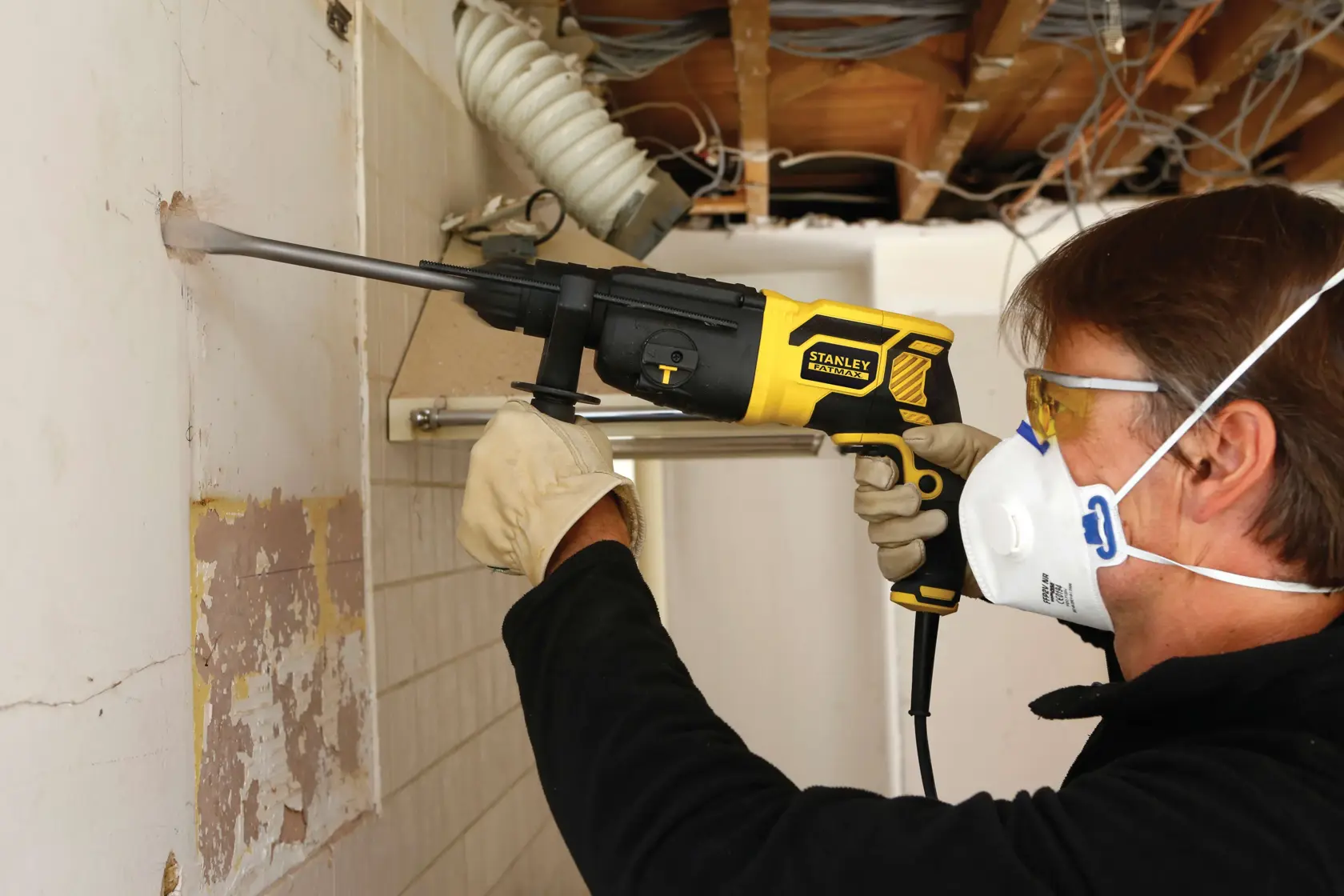 STANLEY FME500K Bohrhammer bei Wandabbruch, Seitenansicht, Bediener mit Handschuhen und Maske.