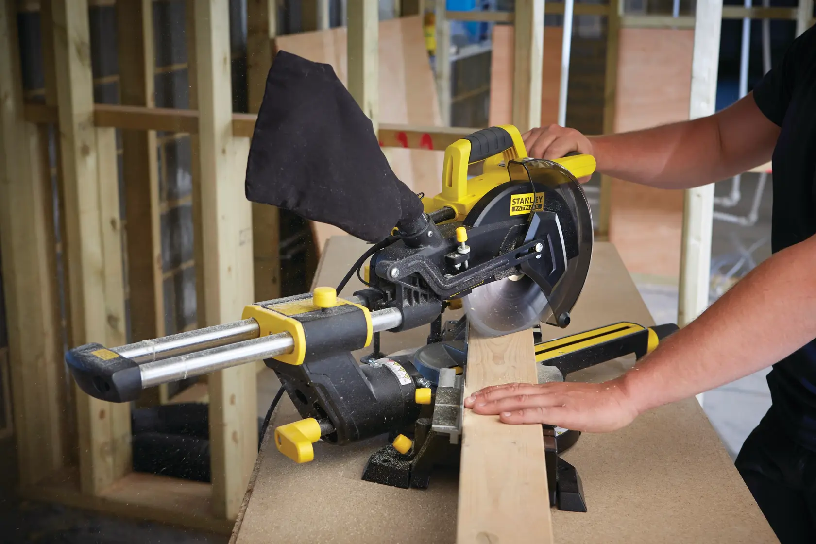 Foto der STANLEY FME721-QS Kapp- und Gehrungssäge beim Schneiden eines Holzbretts auf einer Werkbank.