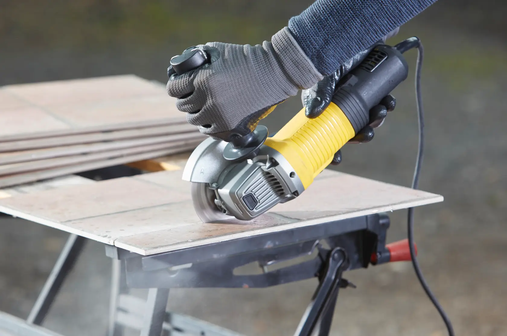 Foto des STANLEY FMEG220 Winkelschleifers beim Fliesenschneiden, Produkt in Benutzung auf Werkbank.