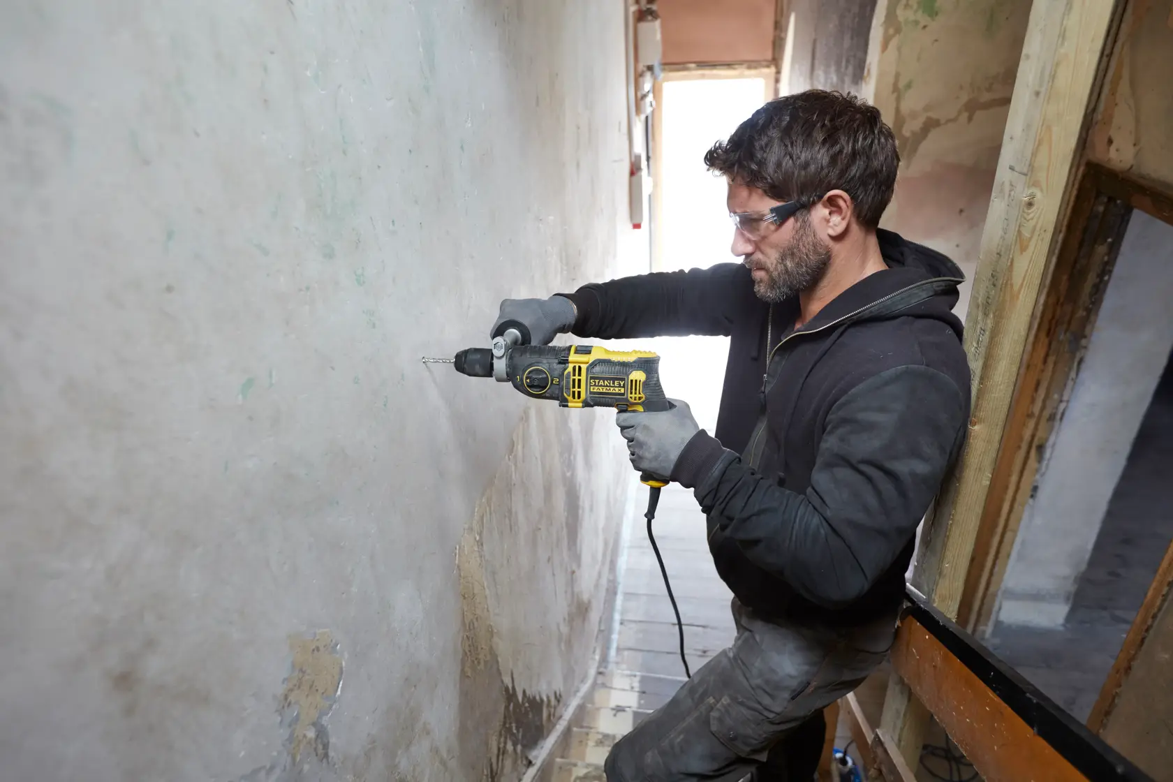Foto einer Person, die mit dem STANLEY FMEH850K Schlagbohrmaschine eine Wand bohrt.
