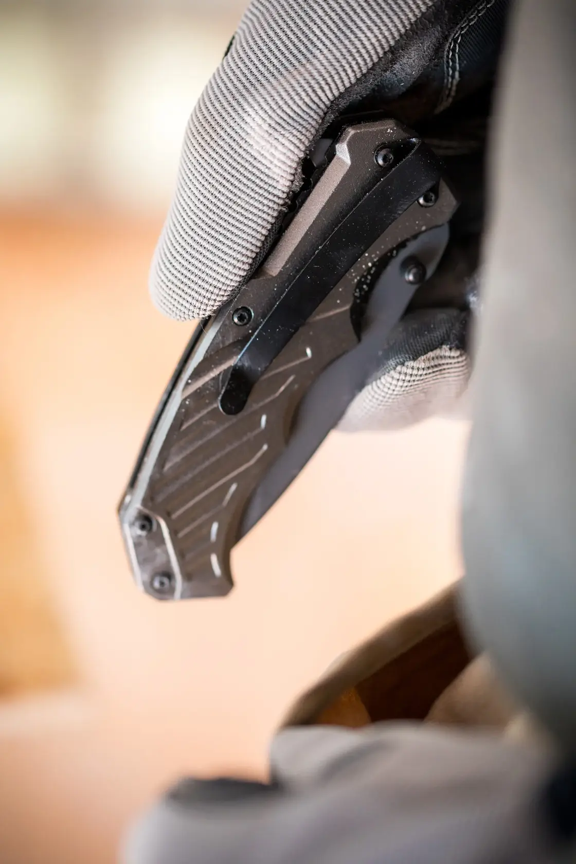 Nahaufnahme einer behandschuhten Hand mit einem STANLEY FMHT0-10311 Klappmesser mit schwarzem Griff.