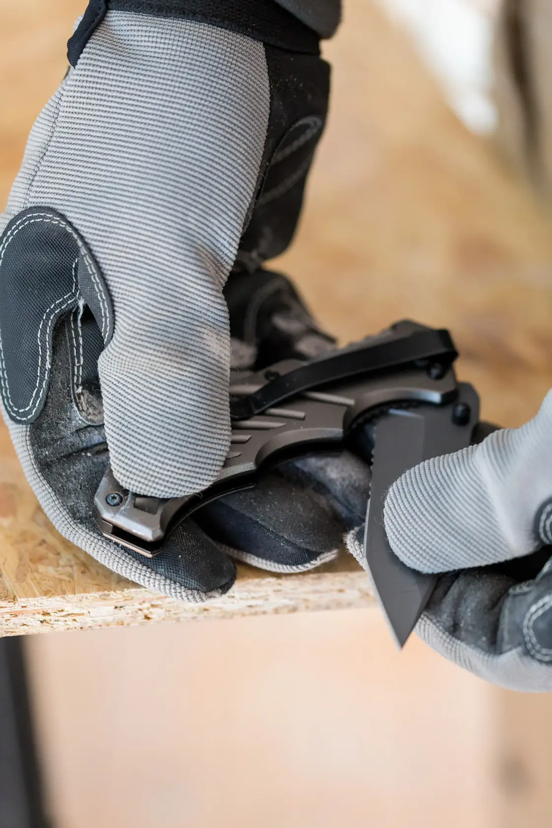 STANLEY FMHT0-10311 Klappmesser in behandschuhten Händen, mit ausgeklappter Klinge auf Werkbank.