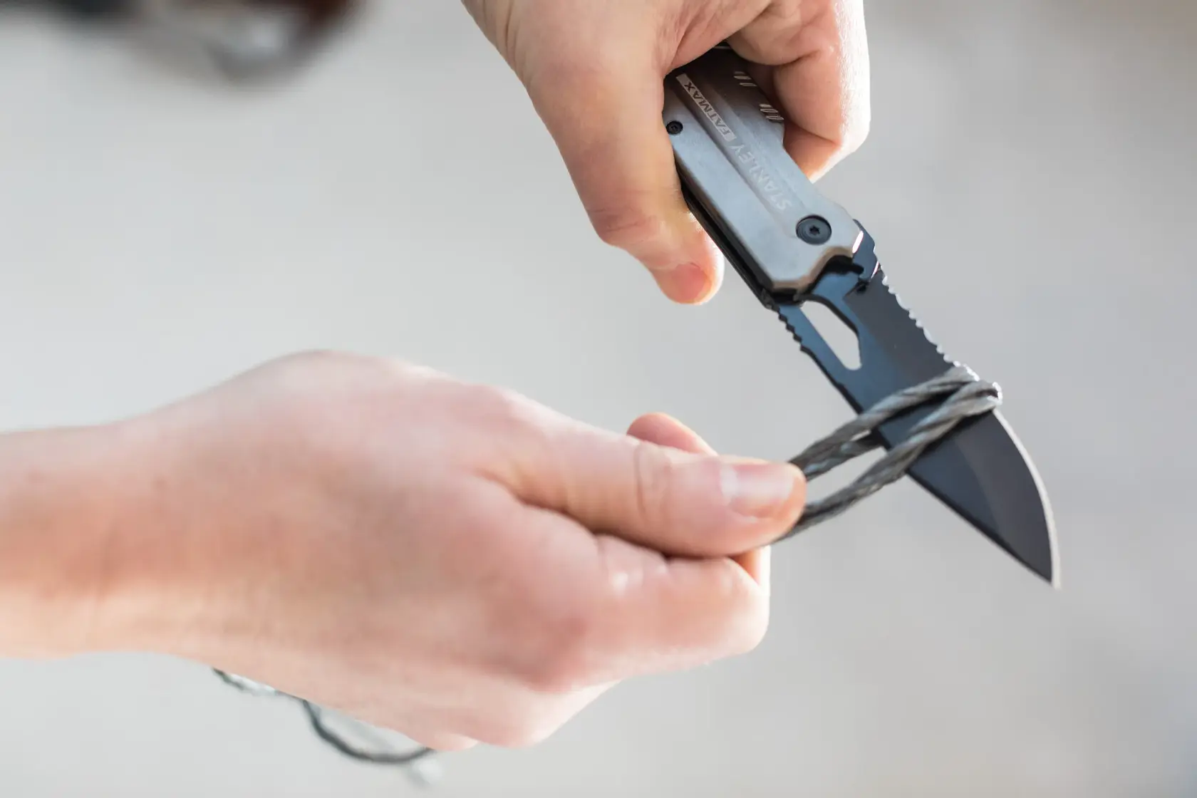 STANLEY FMHT0-10312 Klappmesser schneidet Draht, Nahaufnahme von Händen mit dem Messer.