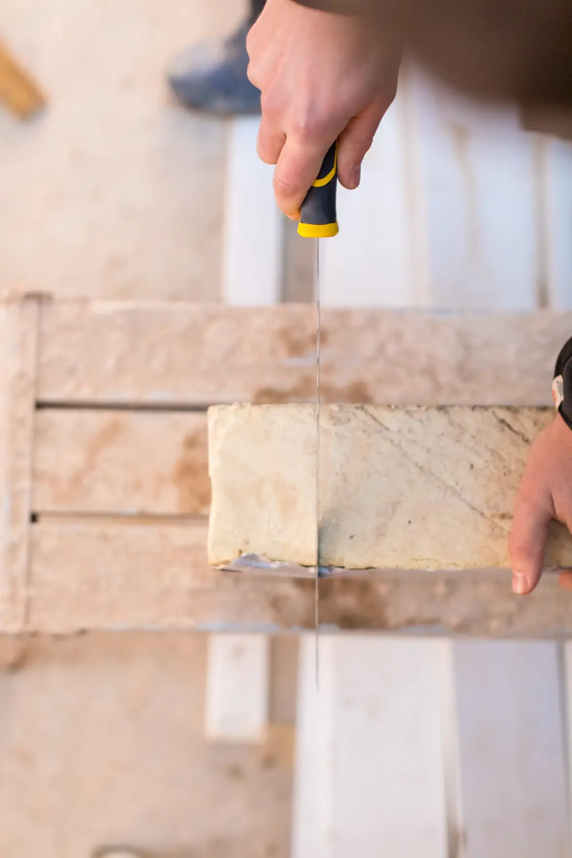 Foto STANLEY FMHT0-10327 Handsäge schneidet Steinblock, Nahaufnahme im Baukontext.