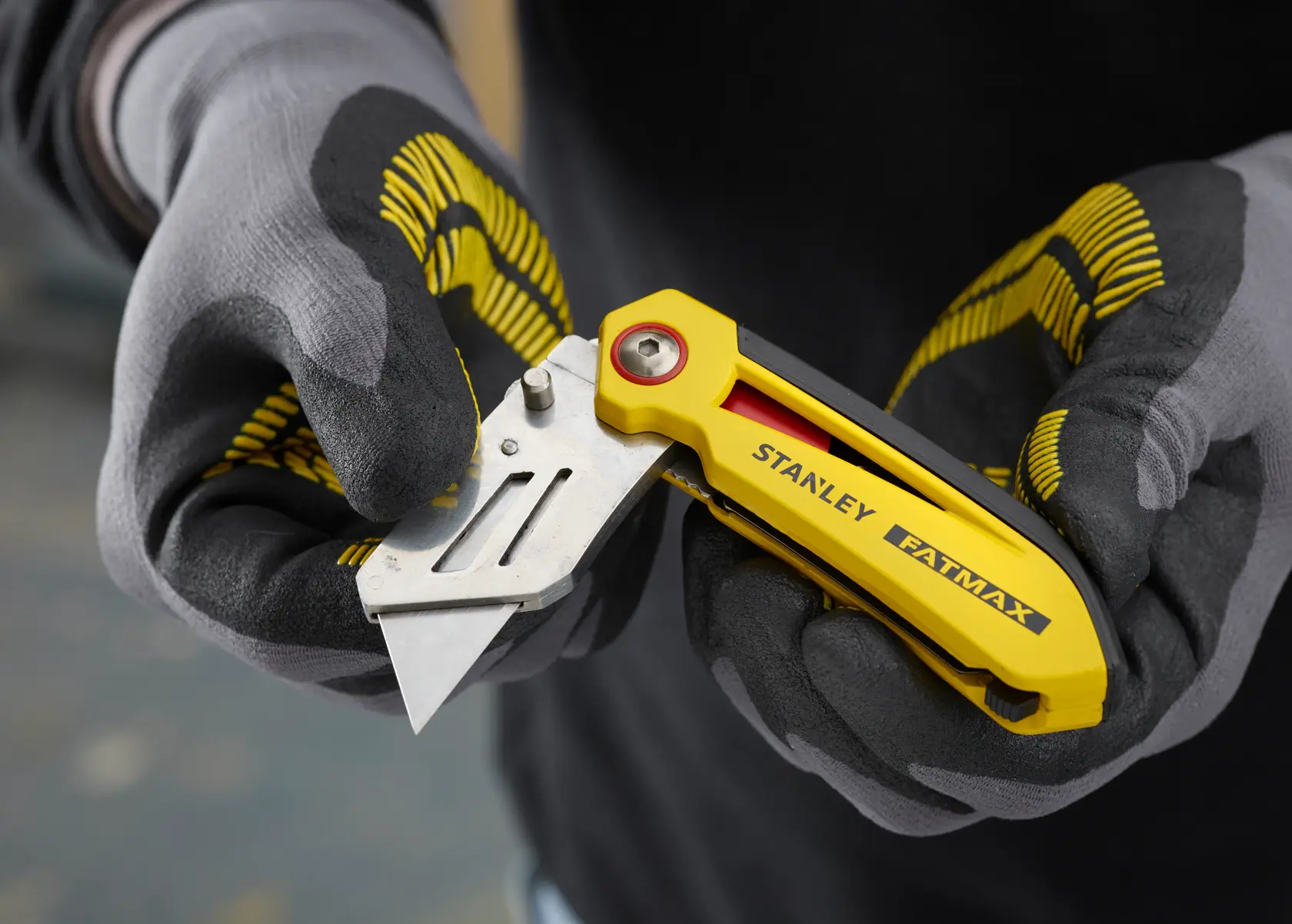 STANLEY FMHT0-10827 gelbes Klappmesser für den Gebrauch in behandschuhter Hand, Nahaufnahme.