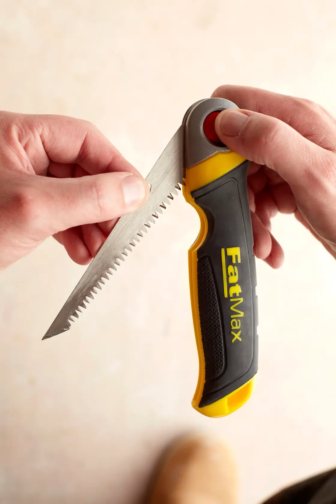 STANLEY FMHT0-20559 Klappsäge mit schwarzem und gelbem FatMax-Griff wird in der Hand gehalten, Nahaufnahme.