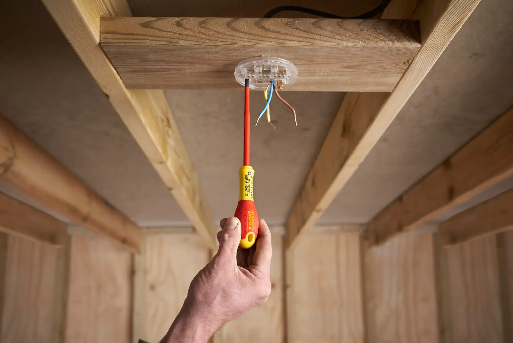 STANLEY FMHT0-62649 isolierter Schraubendreher im Einsatz an Decken-Elektrodose, Holzrahmen innen.