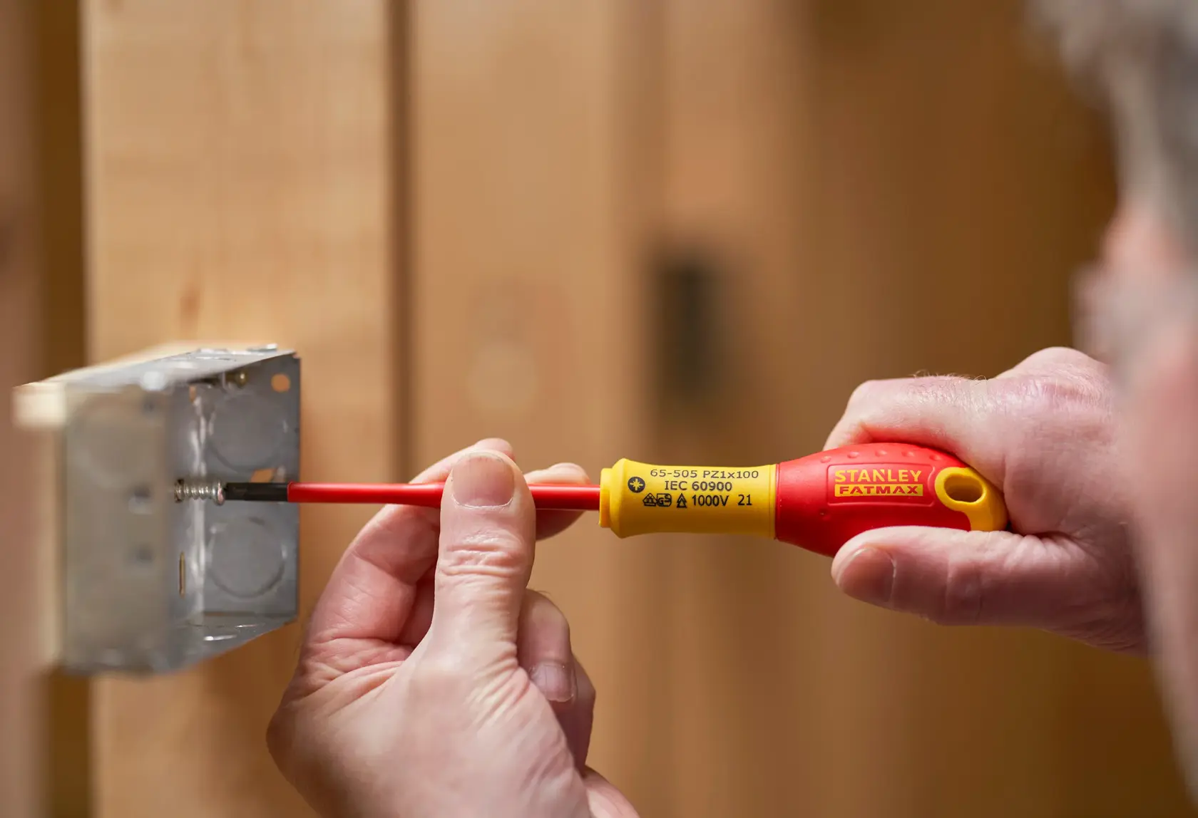 Stanley FMHT0-62649 isolierter Schraubendreher zum Festziehen einer Schraube in einer Metall-Elektrodose, Nahaufnahme.