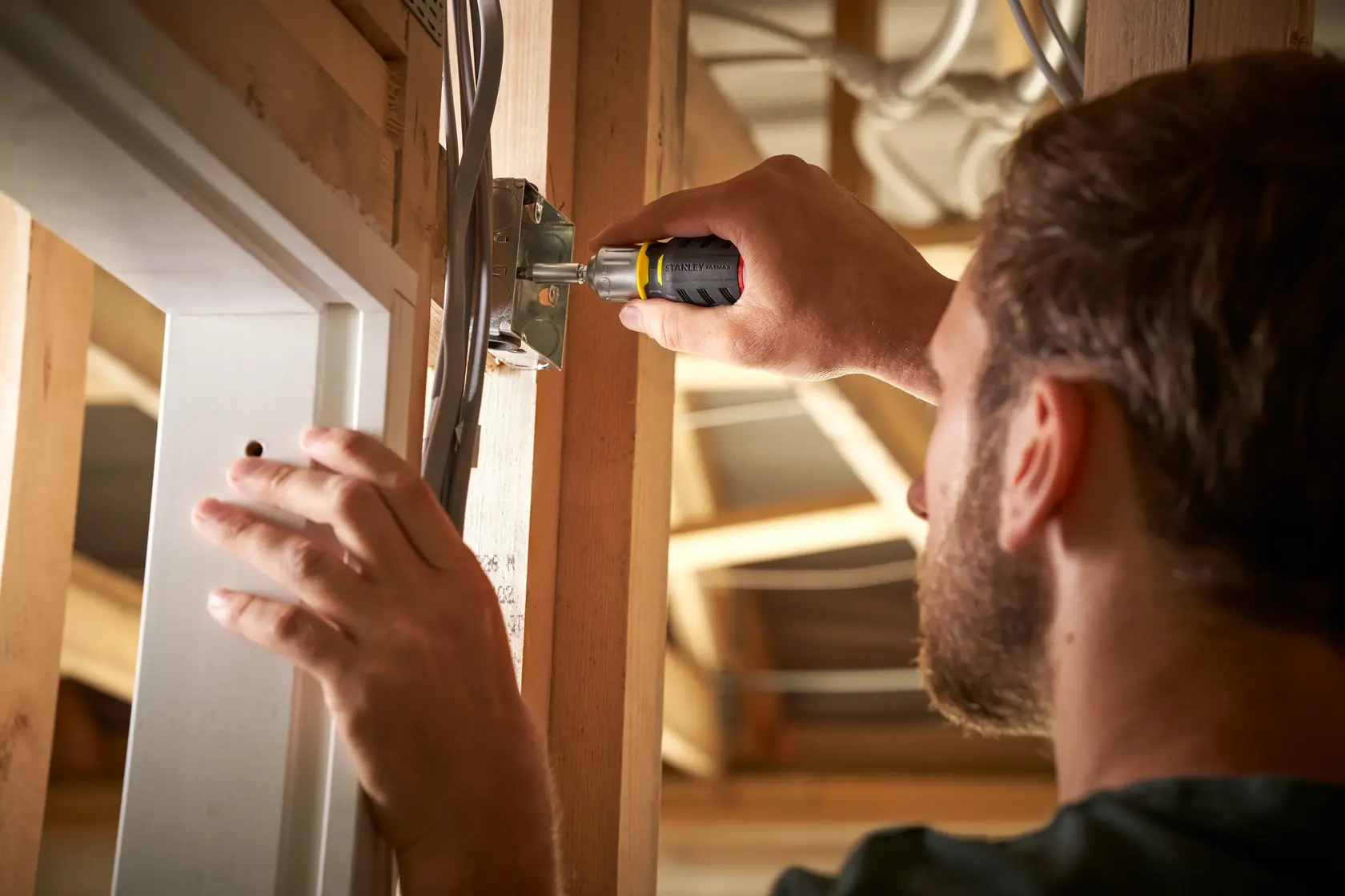 Foto einer Person mit STANLEY FMHT0-62688 Schraubendreher an einer Elektrobox beim Bau.