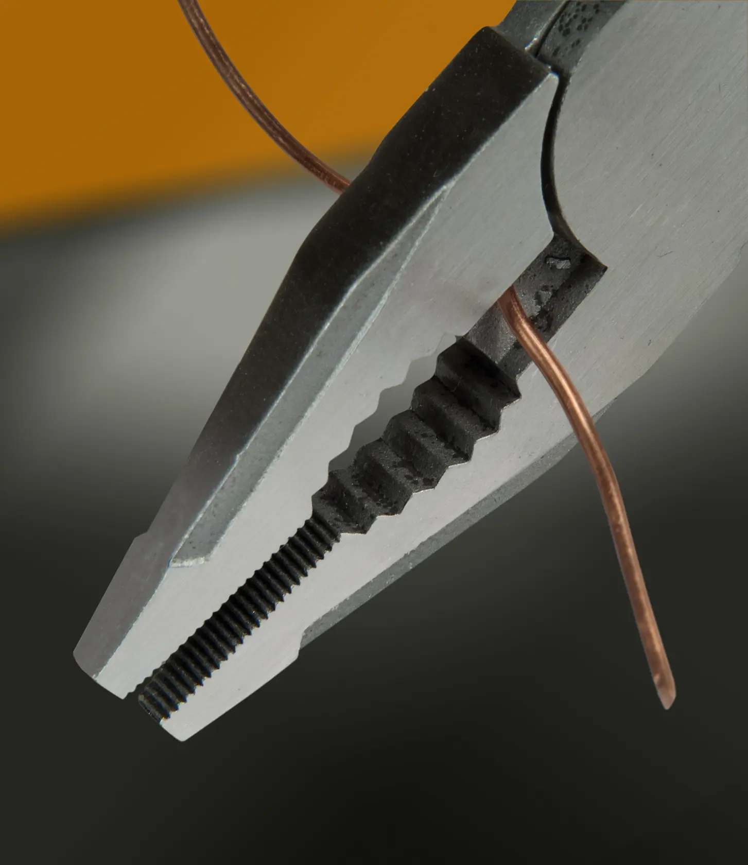 STANLEY FMHT0-72414 Zange Nahaufnahme hält Kupferdraht, Produktfoto mit grau-schwarzem Hintergrund.