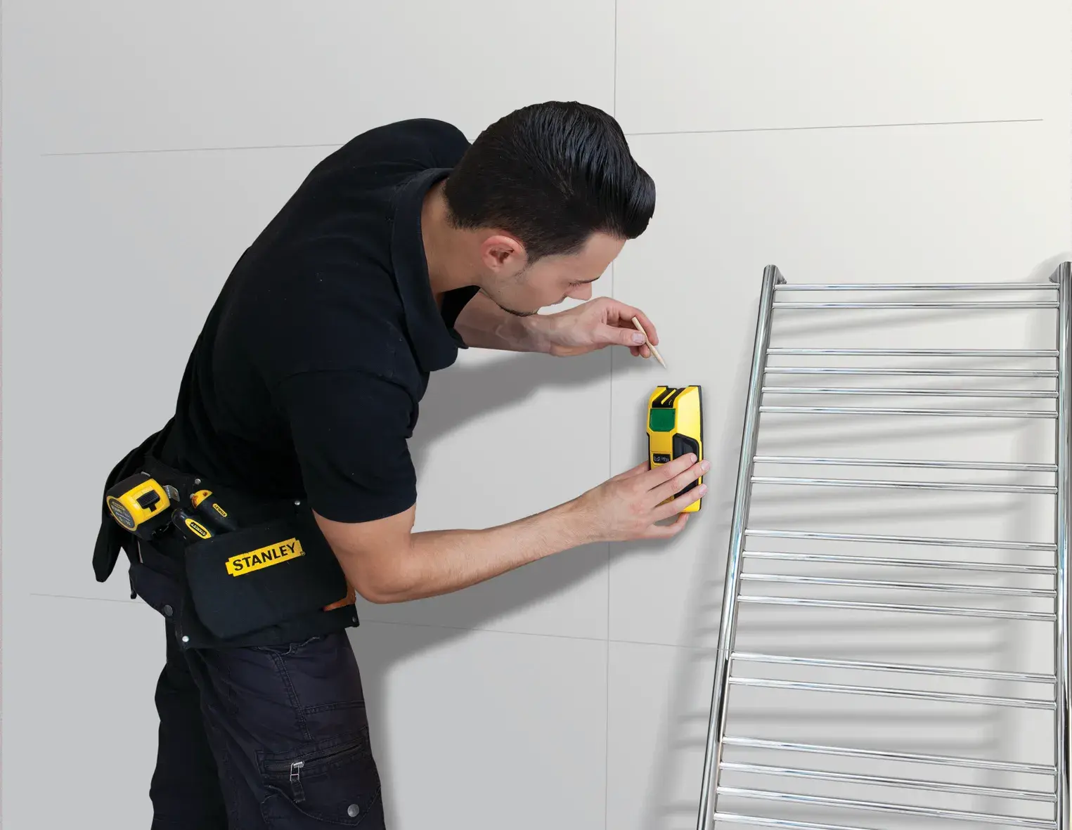 Stanley FMHT0-77407 Wandscanner, genutzt von Arbeiter mit Werkzeugtasche, markiert Wand, silberne Leiter daneben.