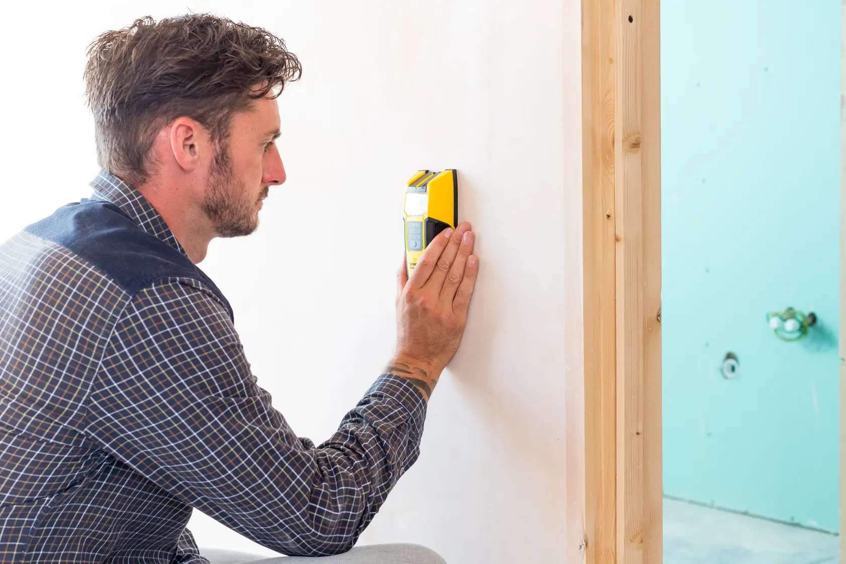 Foto eines Mannes mit STANLEY FMHT0-77407 Balkensucher an weißer Wand, Seitenansicht.