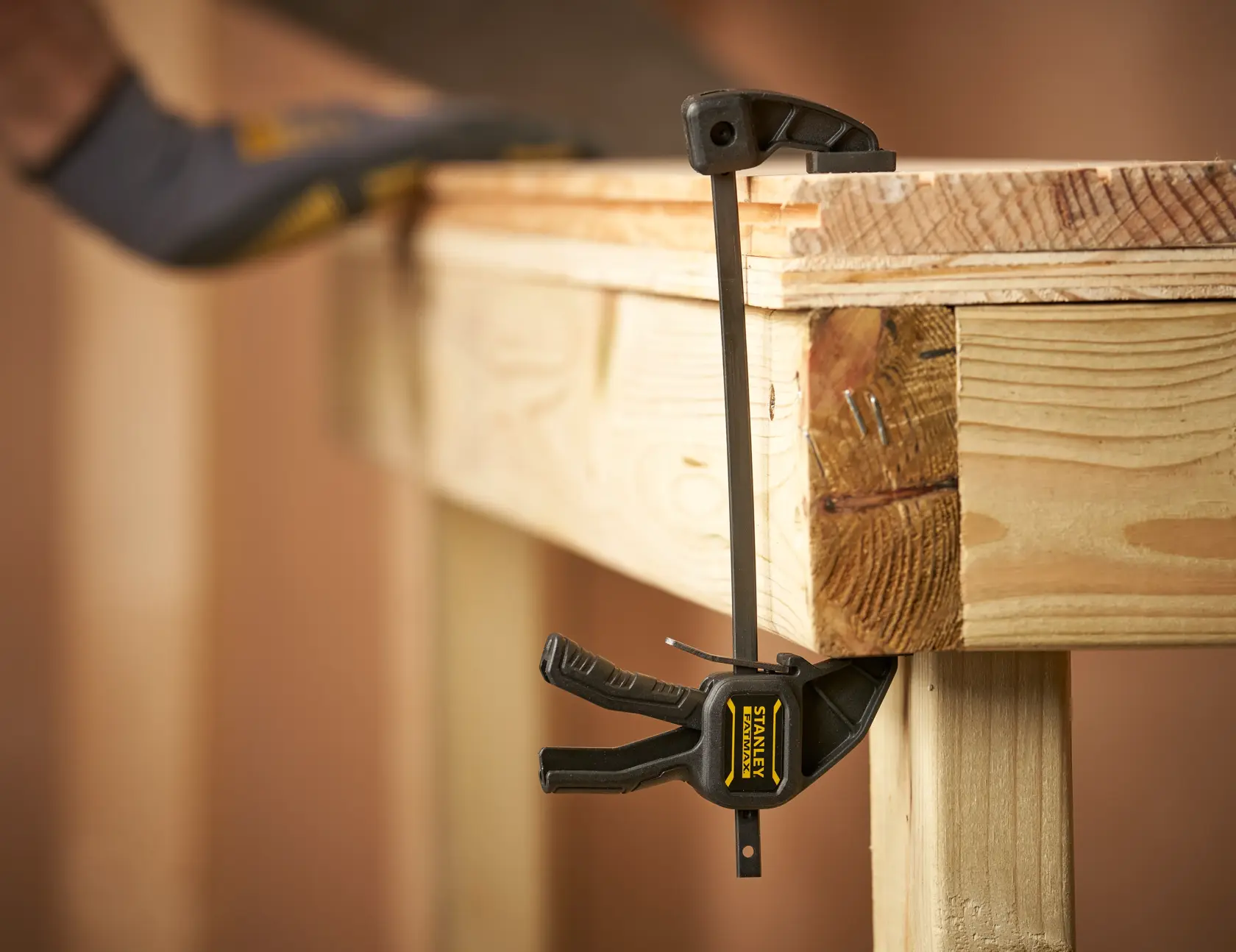 STANLEY FMHT0-83231 Fotografie einer Leimzwinge, die die Kante einer Holzwerkbank sichert