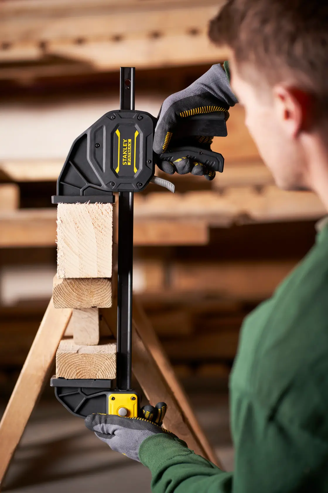STANLEY FMHT0-83239 Fotografie einer Schnellspannzwinge, die Holzblöcke in einer Werkstatt fixiert.