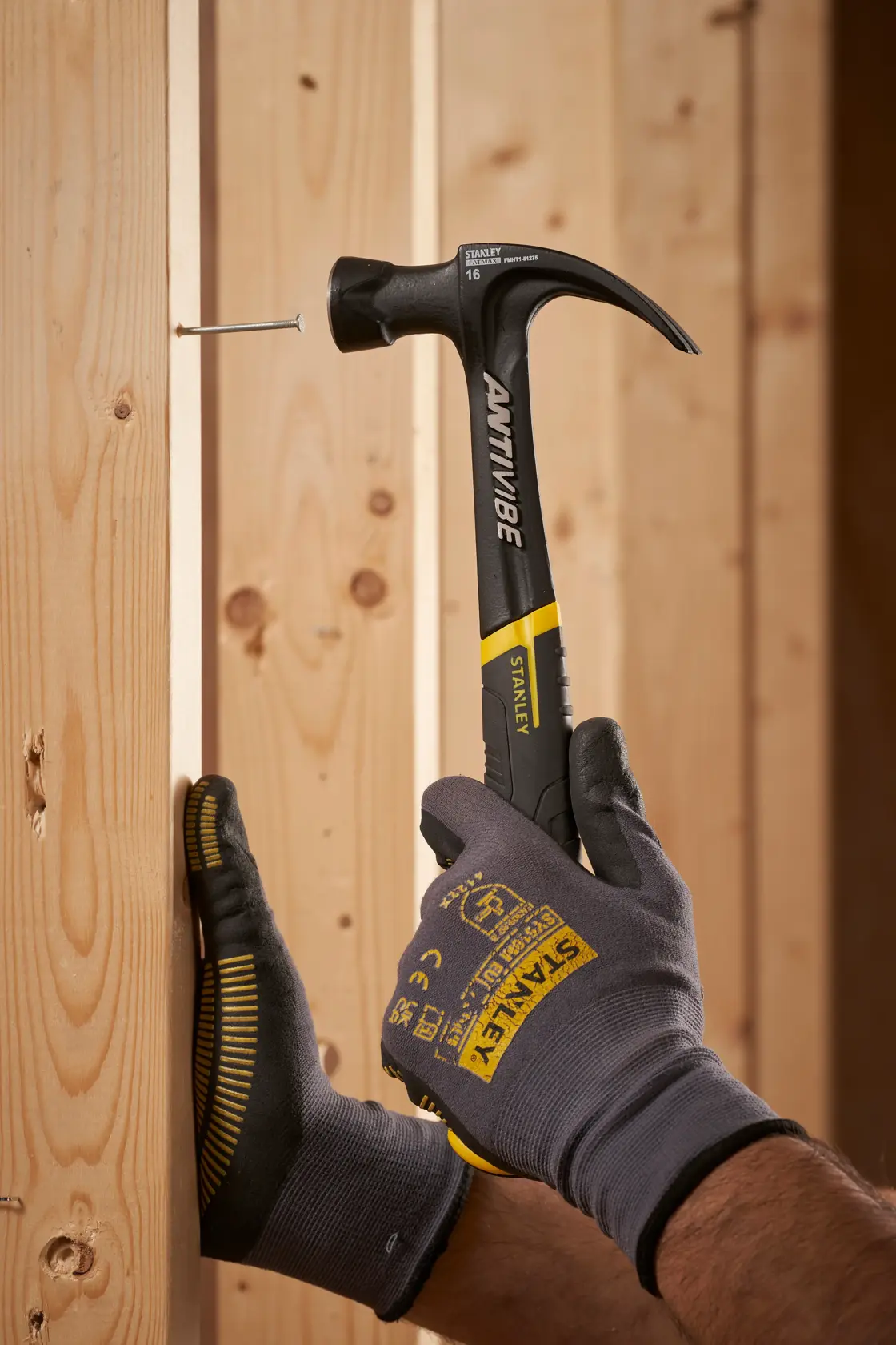Foto des STANLEY FMHT1-51275 Klauenhammers mit schwarz-gelbem Griff beim Einschlagen eines Nagels in einen Holzbalken.