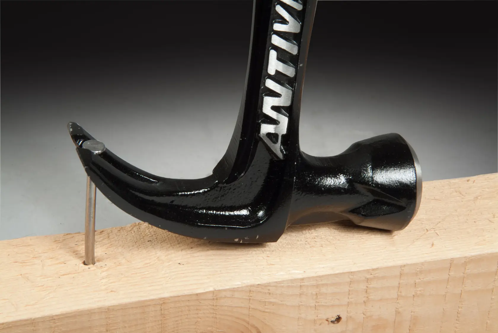 STANLEY FMHT1-51277 Klauenhammer zieht einen Nagel aus Holz, Nahaufnahme seitlich.